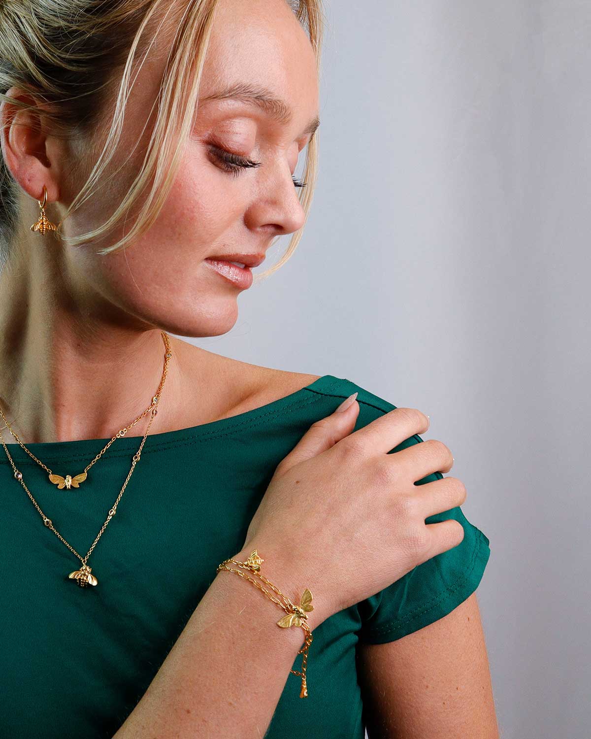 Close-up of gold bracelet showing detailed butterfly and bee charms