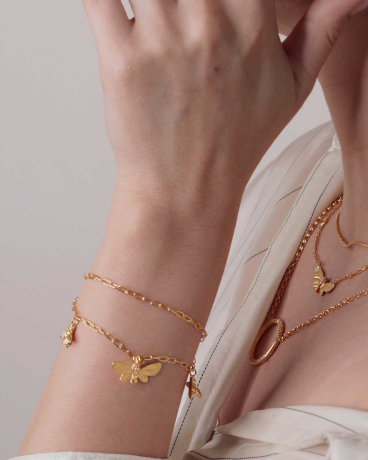 Side view of gold bracelet highlighting adjustable chain and butterfly and bee charms