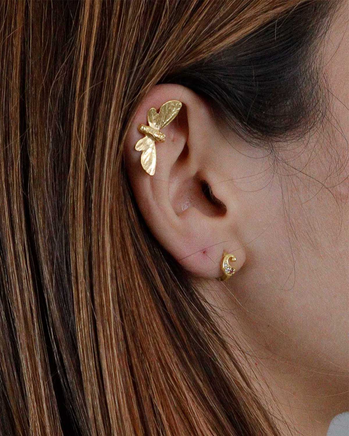 Close-up of gold butterfly stud earrings showing intricate handcrafted details