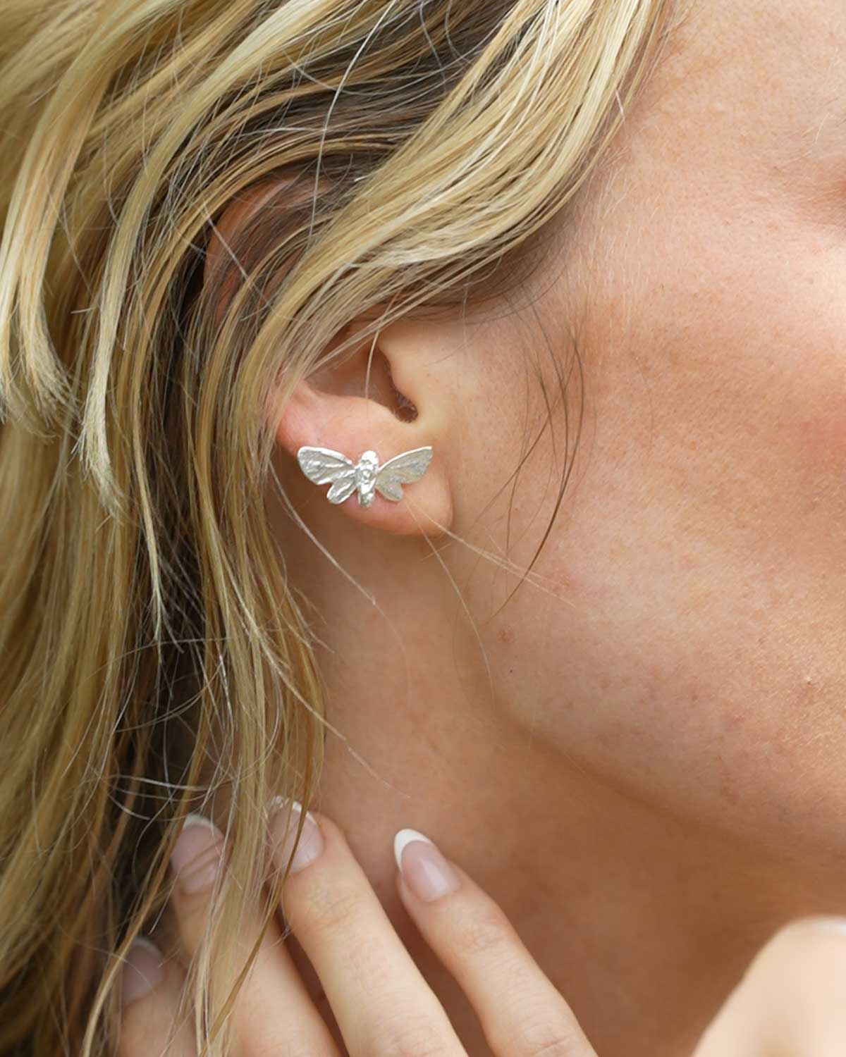 Close-up of silver butterfly studs showcasing intricate detailing and polished finish