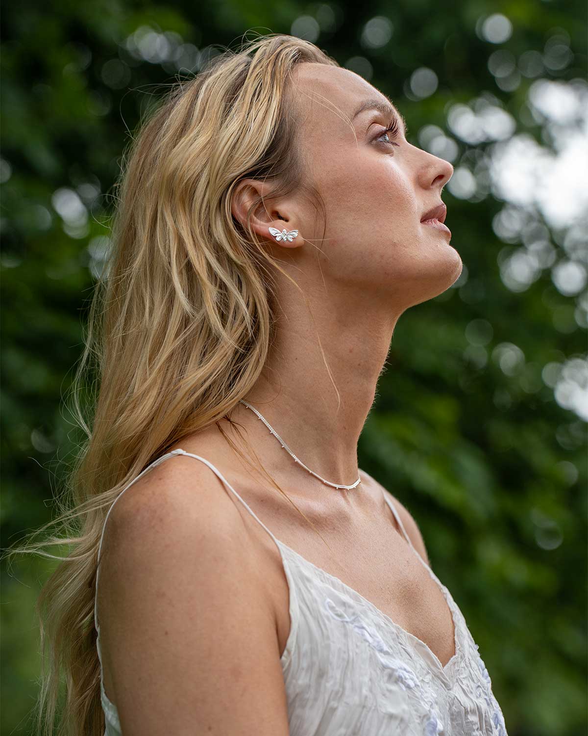 Model wearing sterling silver butterfly stud earrings, highlighting delicate design