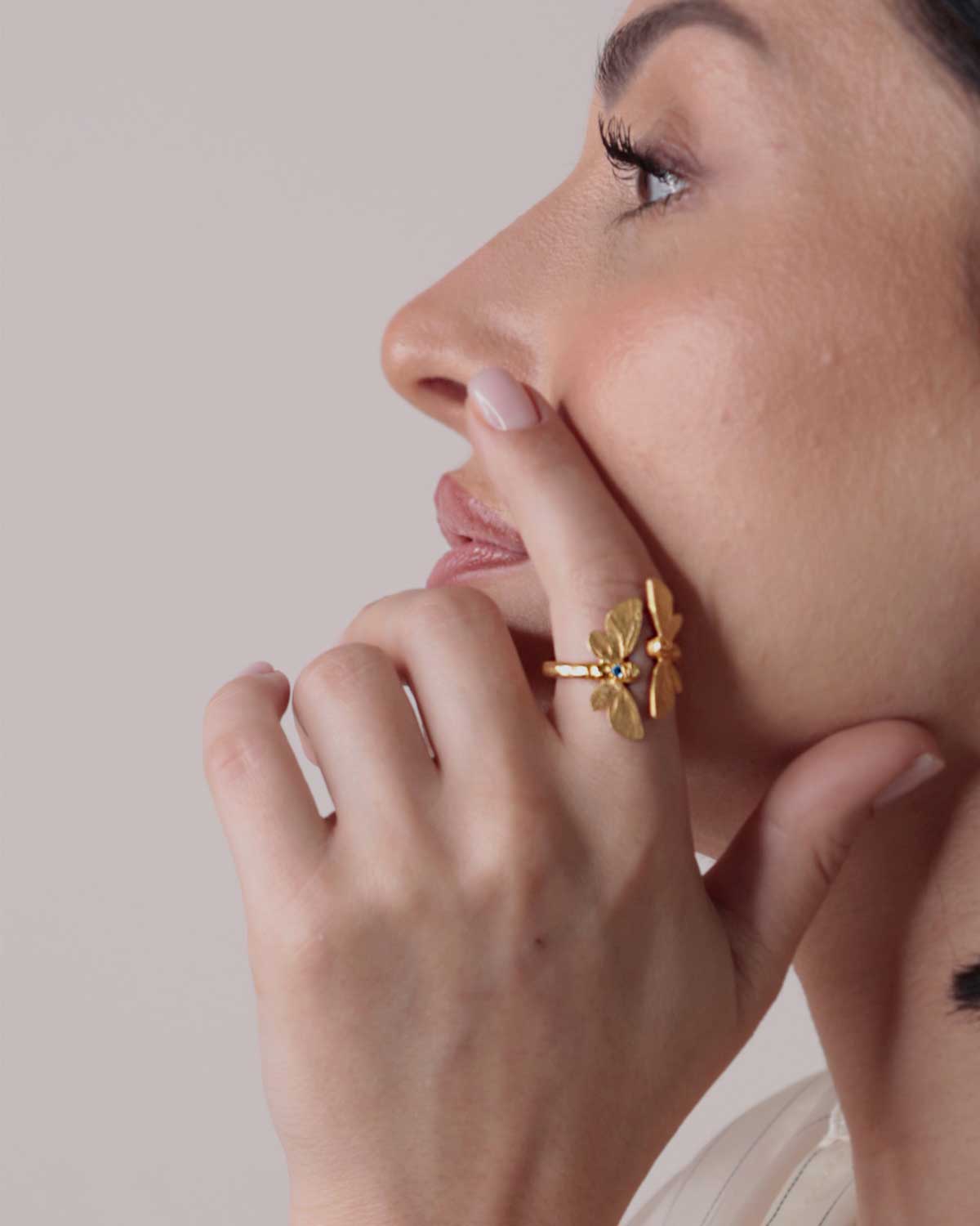 Close-up of gold ring featuring detailed butterfly design and Swiss Blue Topaz gemstone