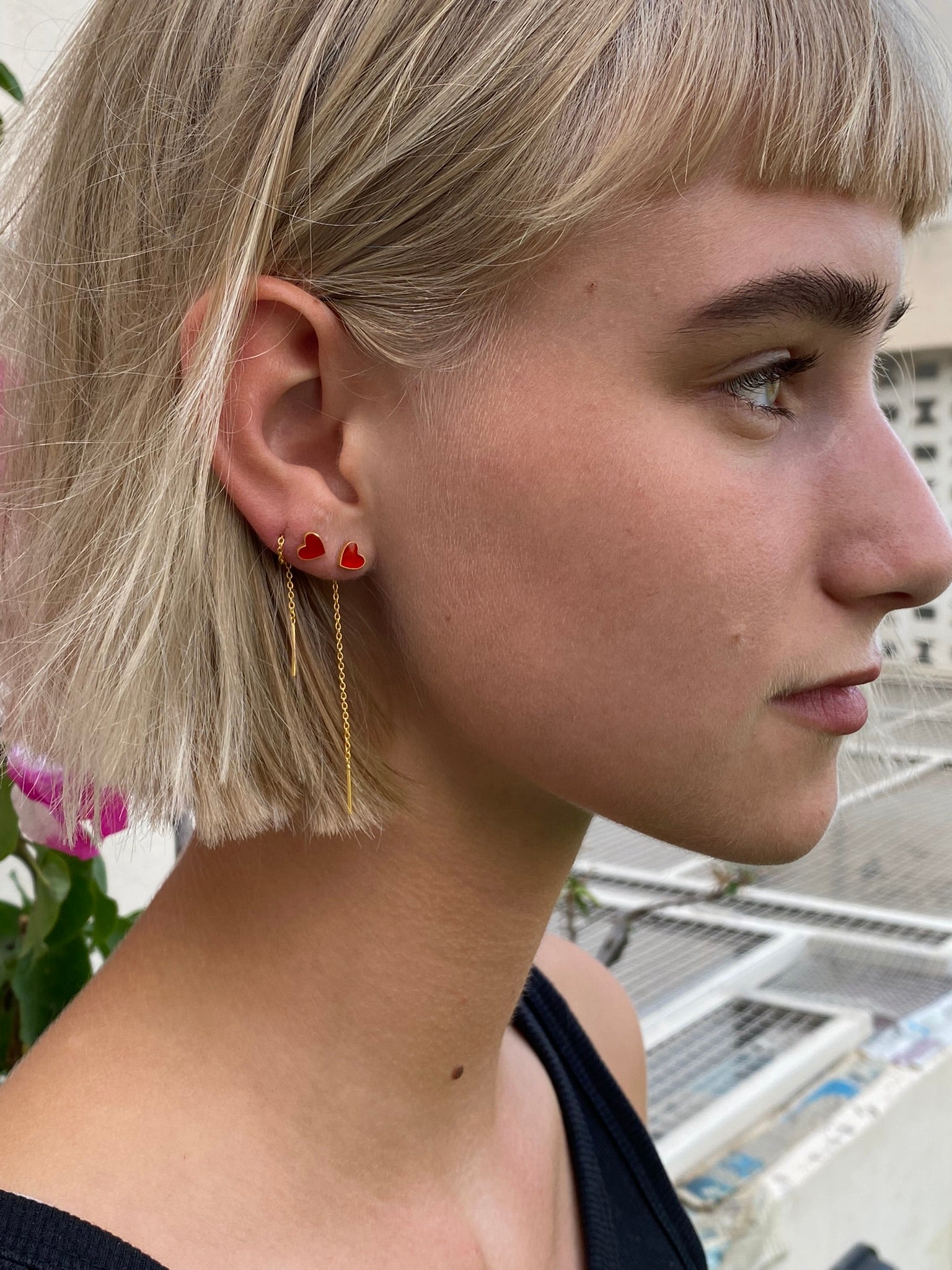Gold heart earrings styled through multiple lobe piercings