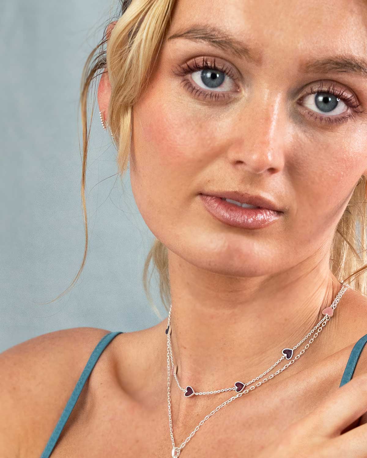 Close-up of gold necklace with lipstick colour enamel heart pendant