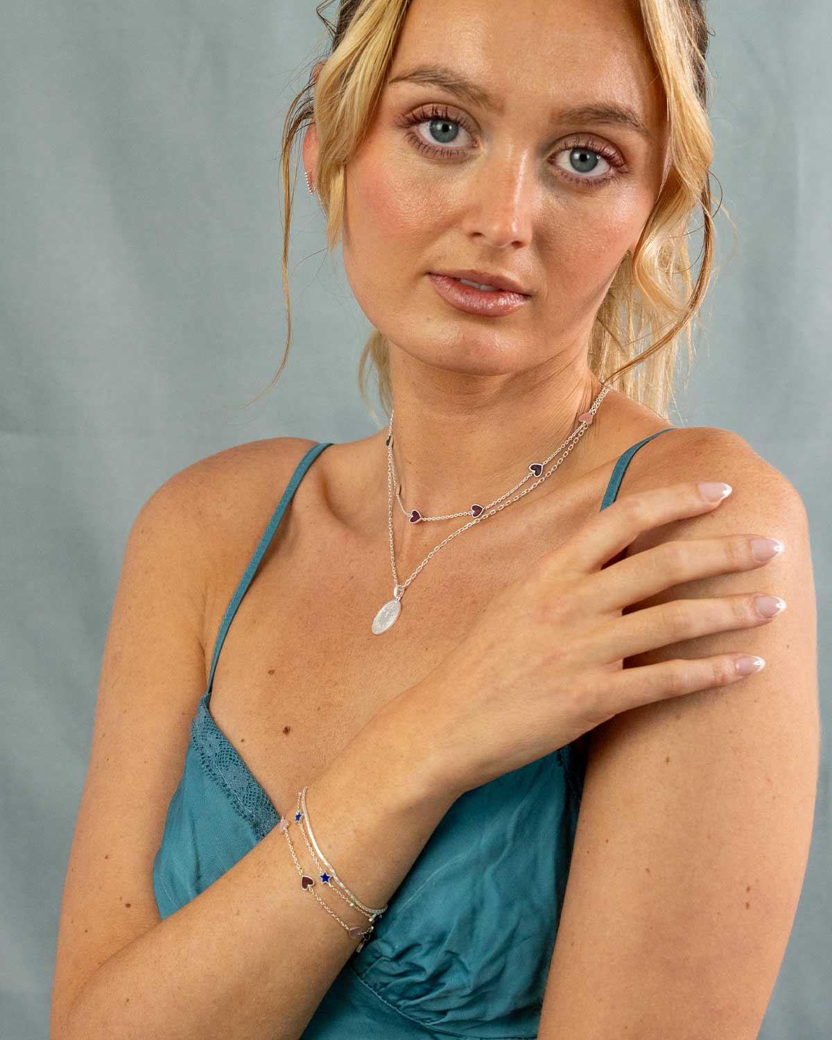 Silver heart bracelet layered with other bracelets for a stacked look