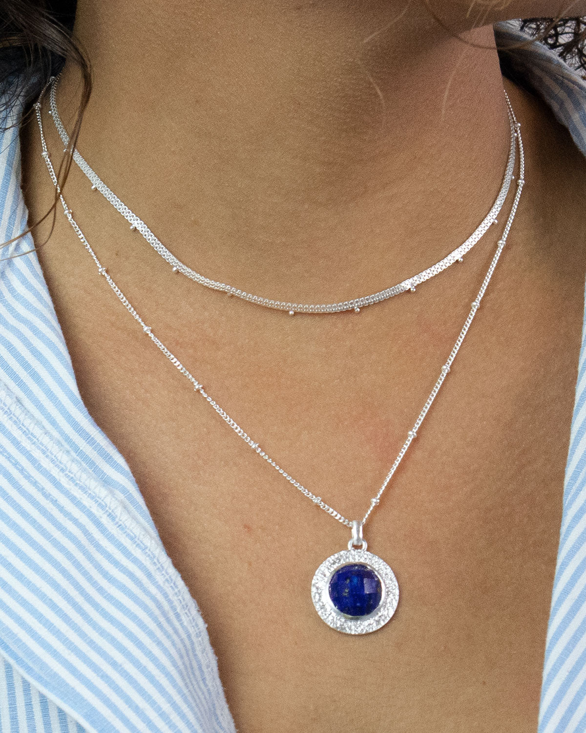 Deep blue lapis lazuli gemstone set in a circular sterling silver pendant