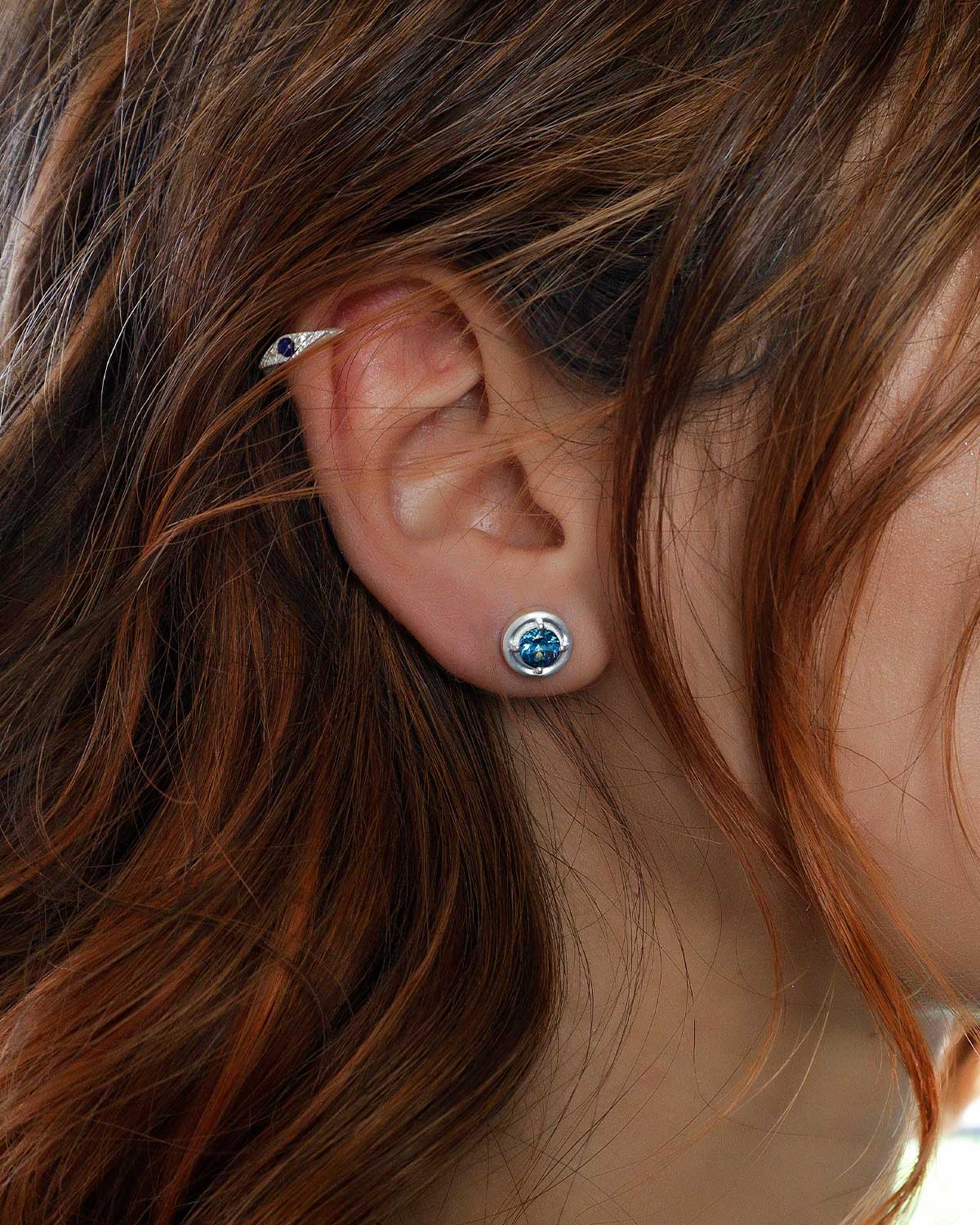 Close-up of sterling silver stud earrings with rich blue topaz stones