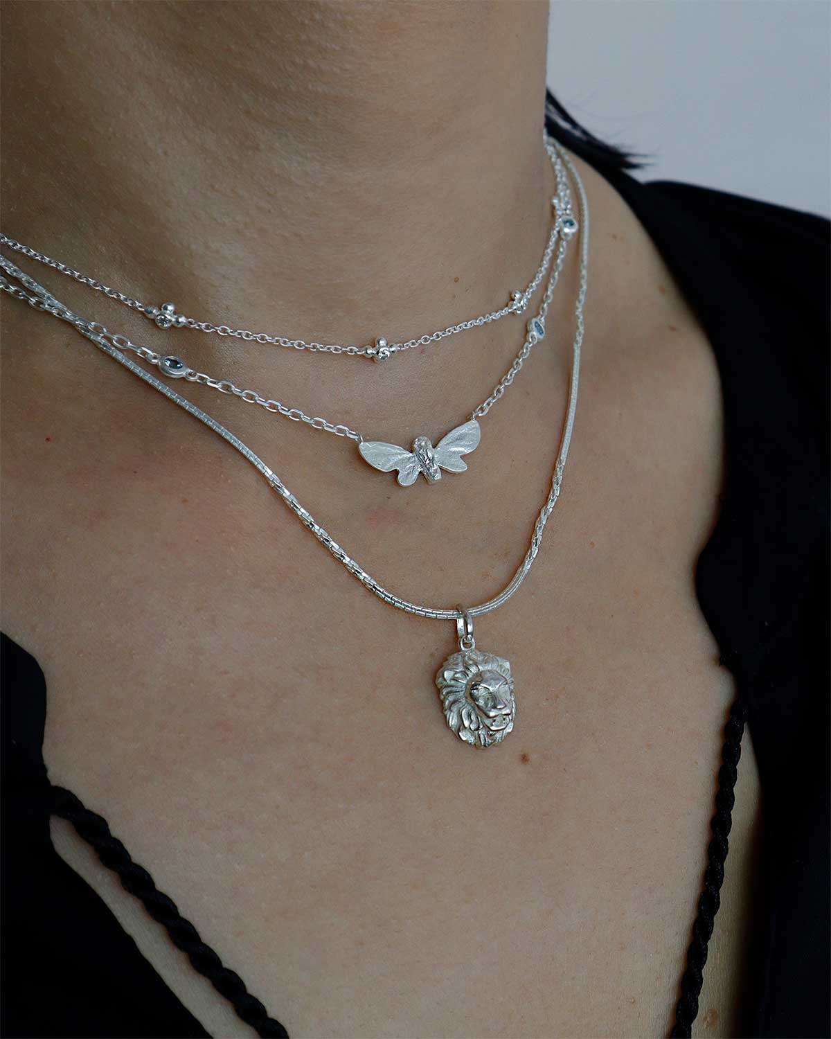 Lion pendant silver necklace styled in a layered look with textured chain detail