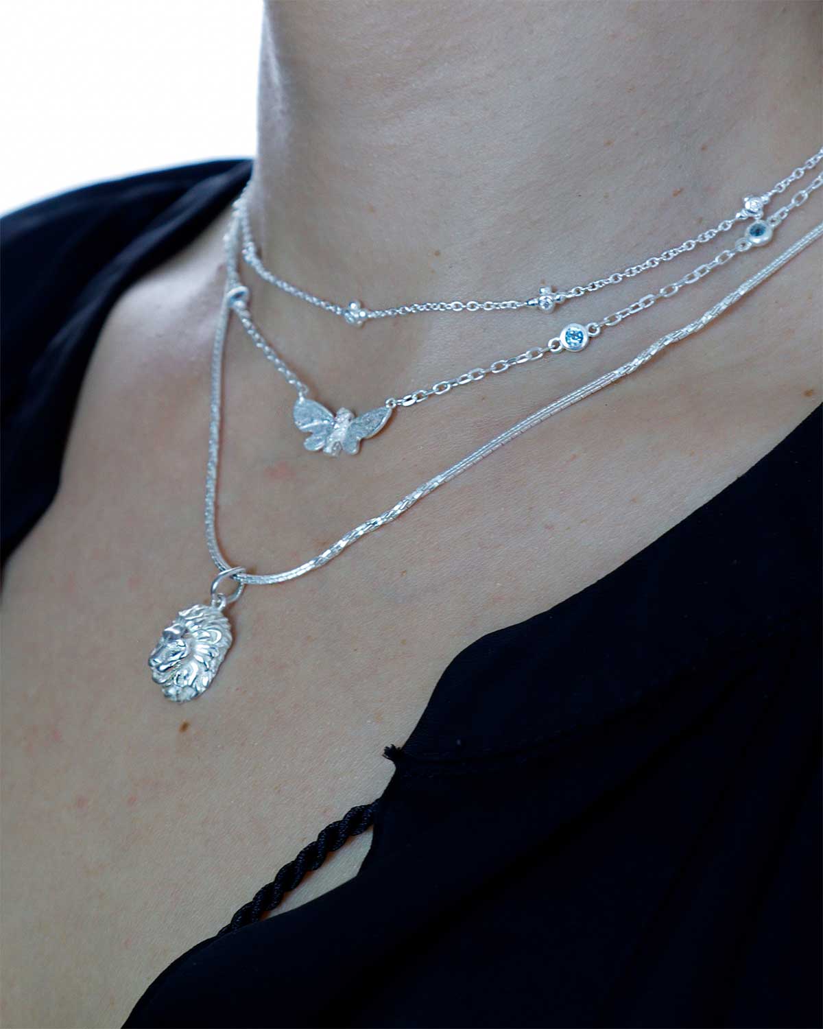 Model wearing a silver lion pendant necklace with textured chain