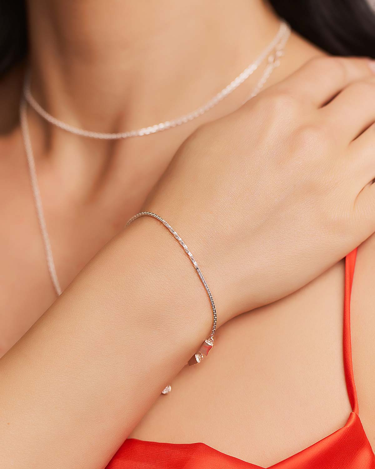 Model wearing adjustable sterling silver bracelet with two chain patterns