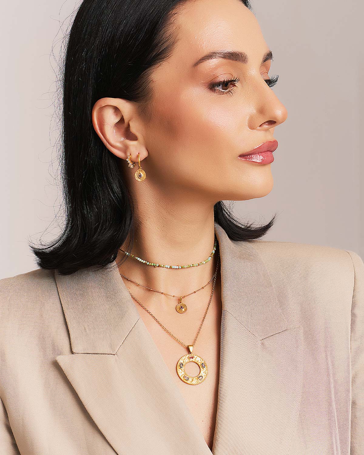 Model wearing a gold necklace with multicolour tourmaline gemstones