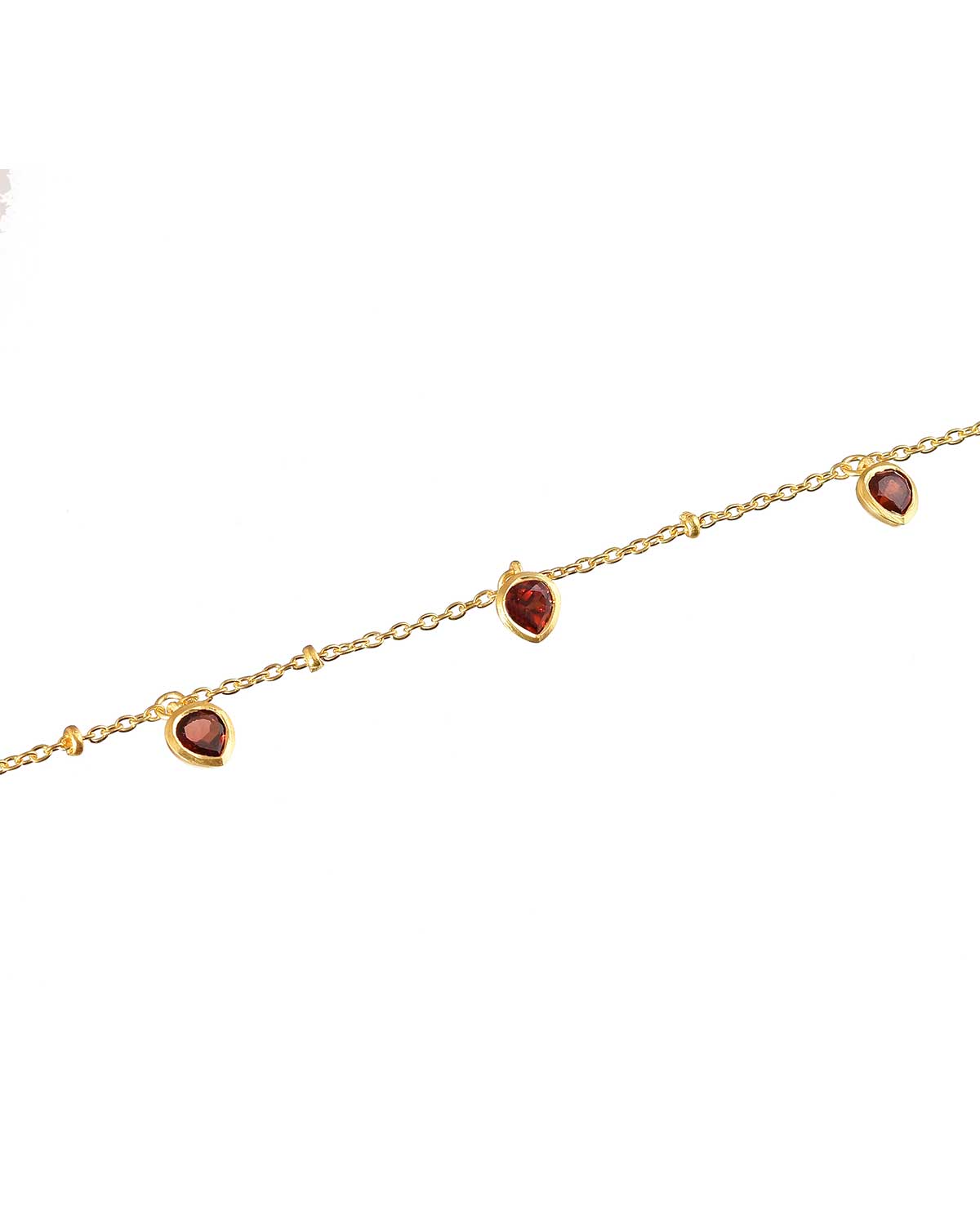 Detailed view of a garnet heart charm on a gold bracelet