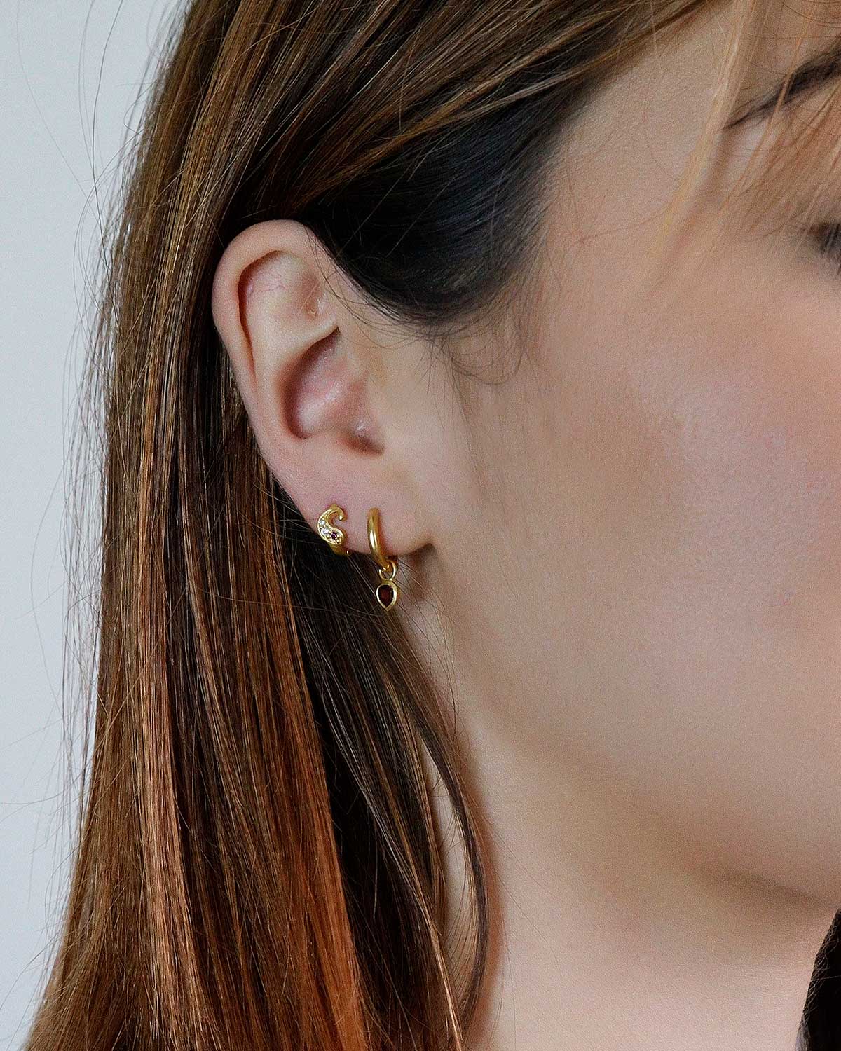 Side profile of gold mini hoop earrings with removable garnet heart charms