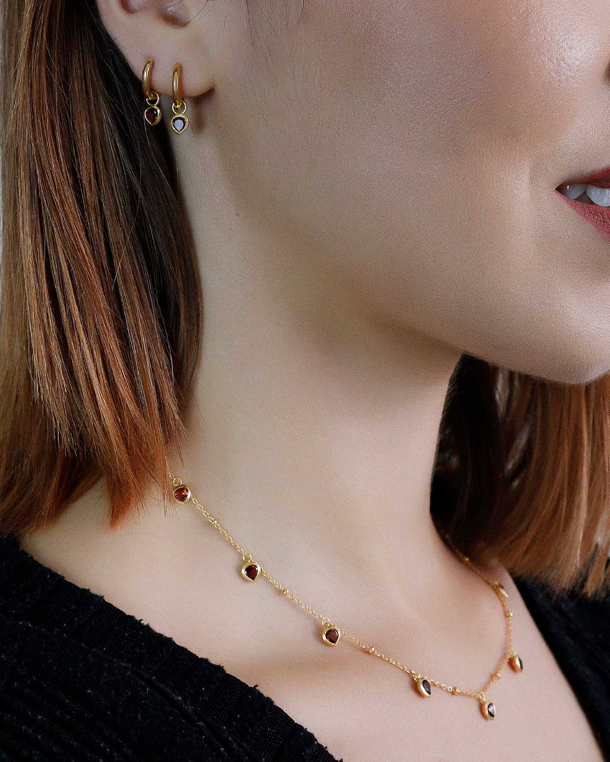 Close-up of a gold necklace with a garnet heart charm and polished finish