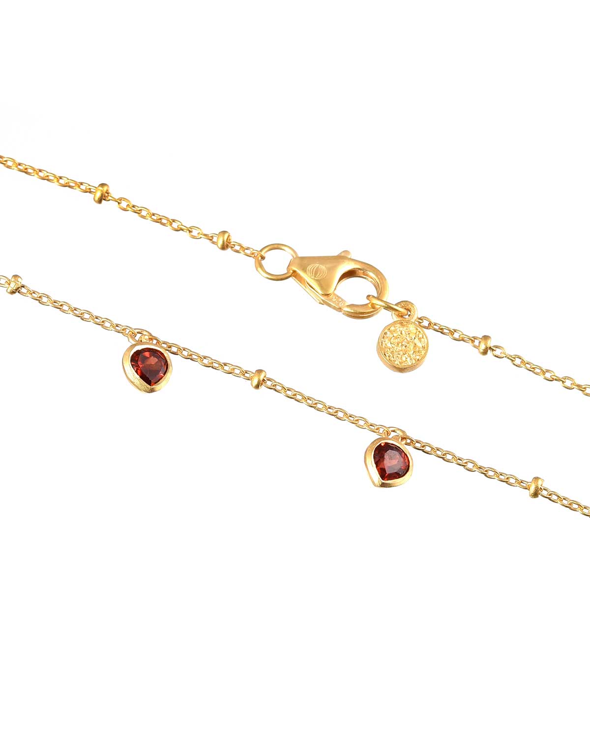 Gold necklace with a garnet heart charm styled as a gift for loved ones