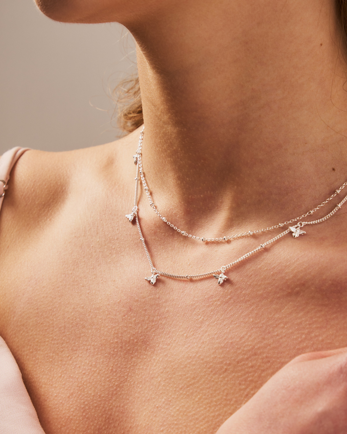 Model wearing adjustable sterling silver necklace with multiple bee charms