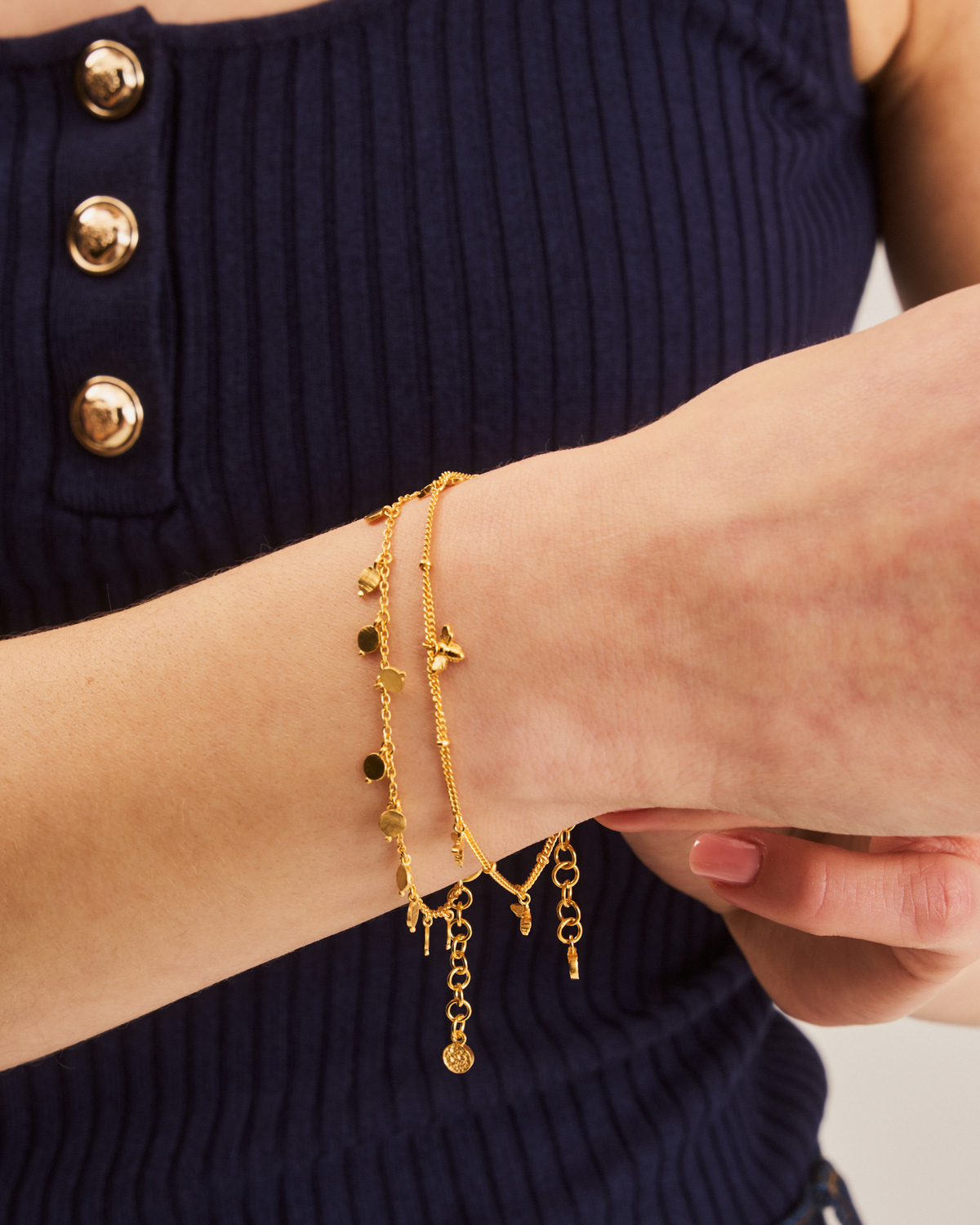 Gold adjustable bracelet with bee details styled with layered jewellery