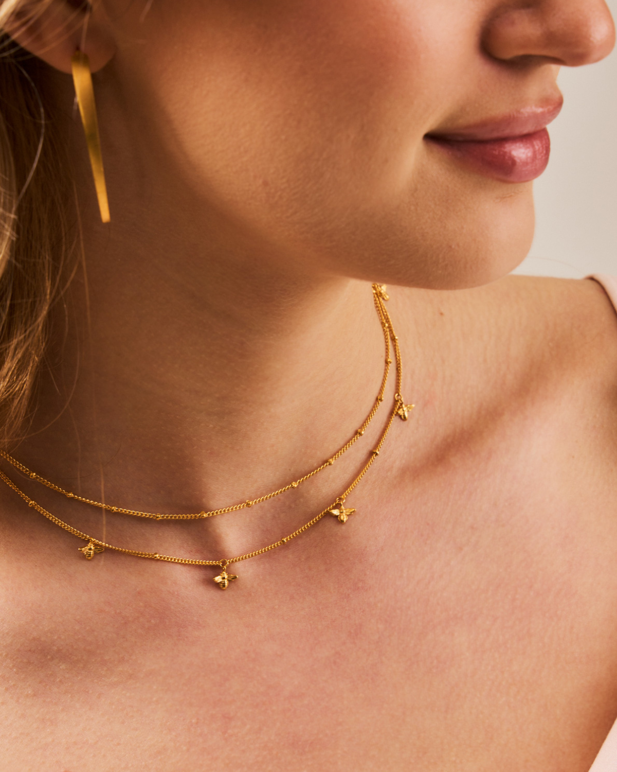 Close-up of handcrafted bee details on a gold adjustable necklace