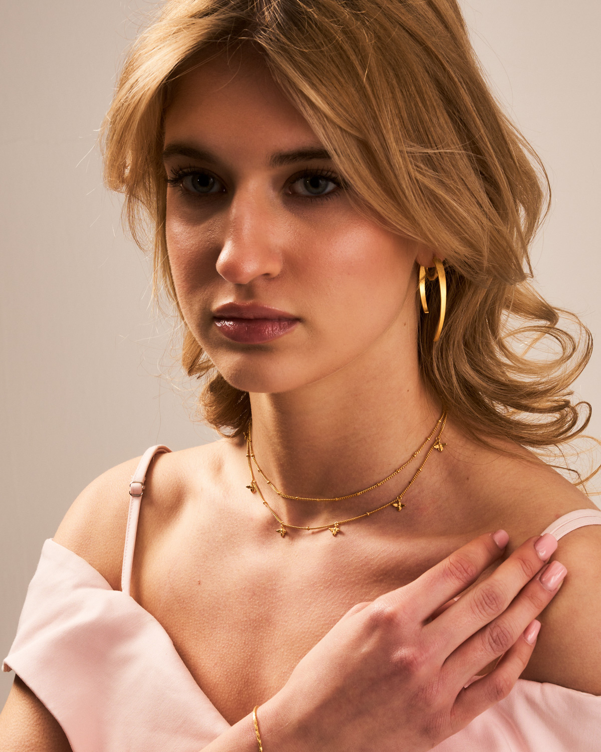Gold bee necklace layered with other necklaces for a statement look