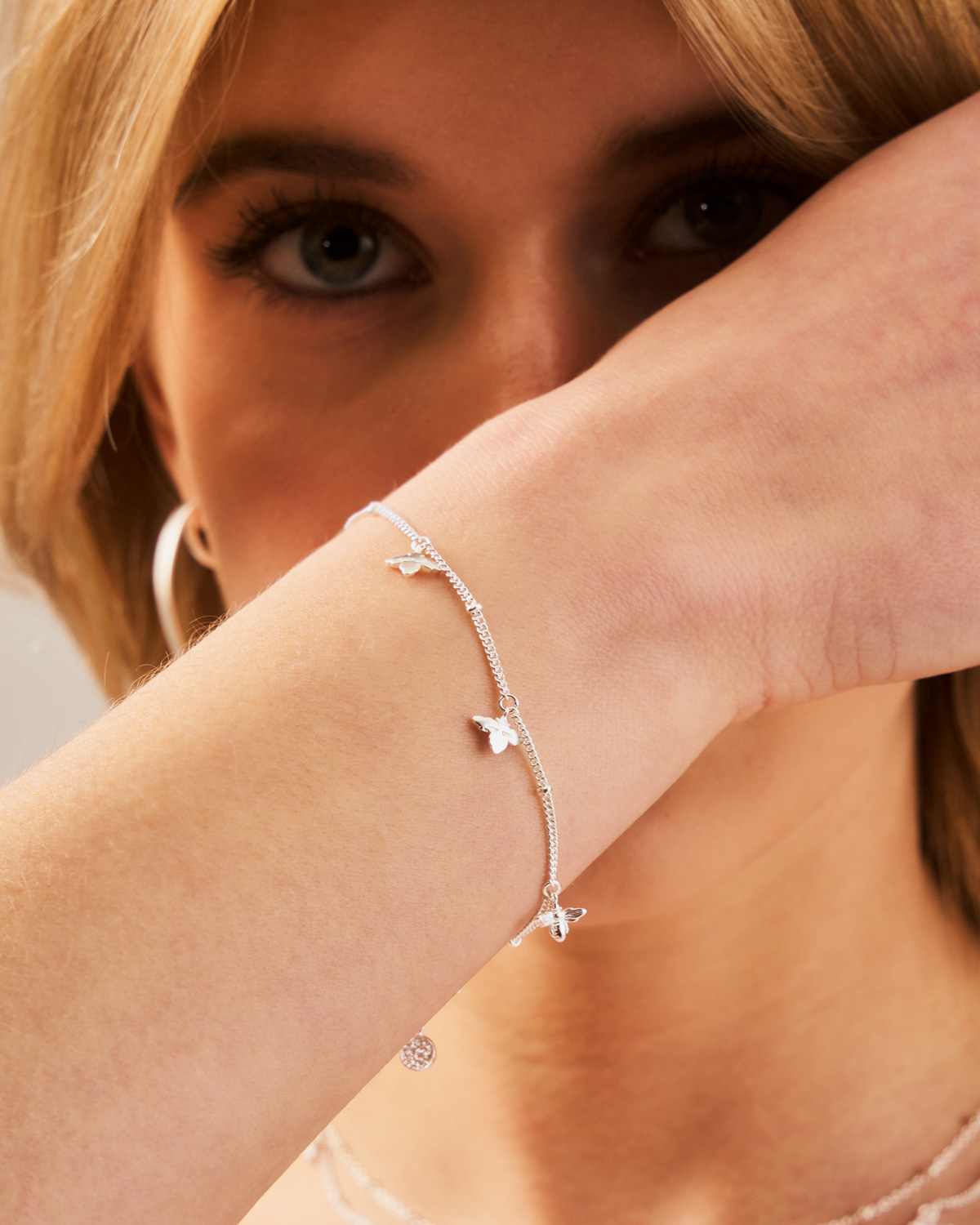 Silver adjustable bracelet with bee details layered with other bracelets