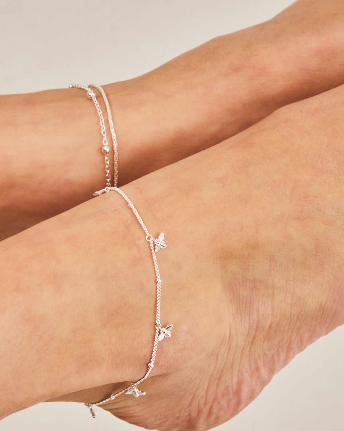 Close-up of sterling silver anklet with detailed handcrafted bee charms
