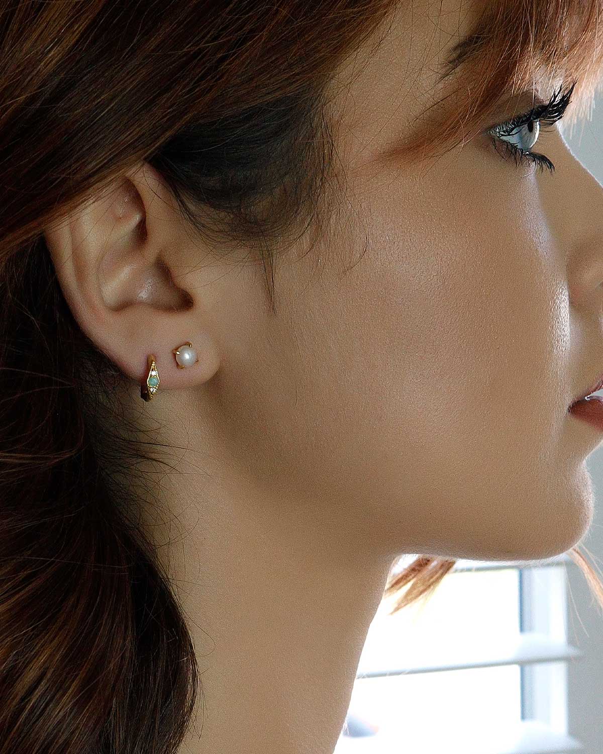 Close-up of gold stud earrings with natural pearl detail