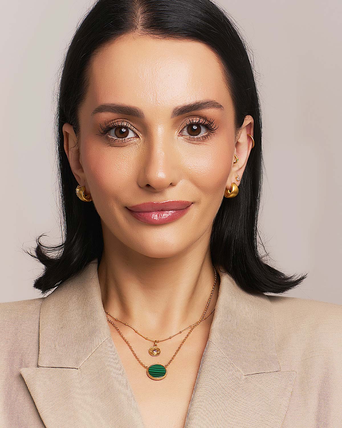 Model wearing mini chunky gold hoop earrings with a satin finish