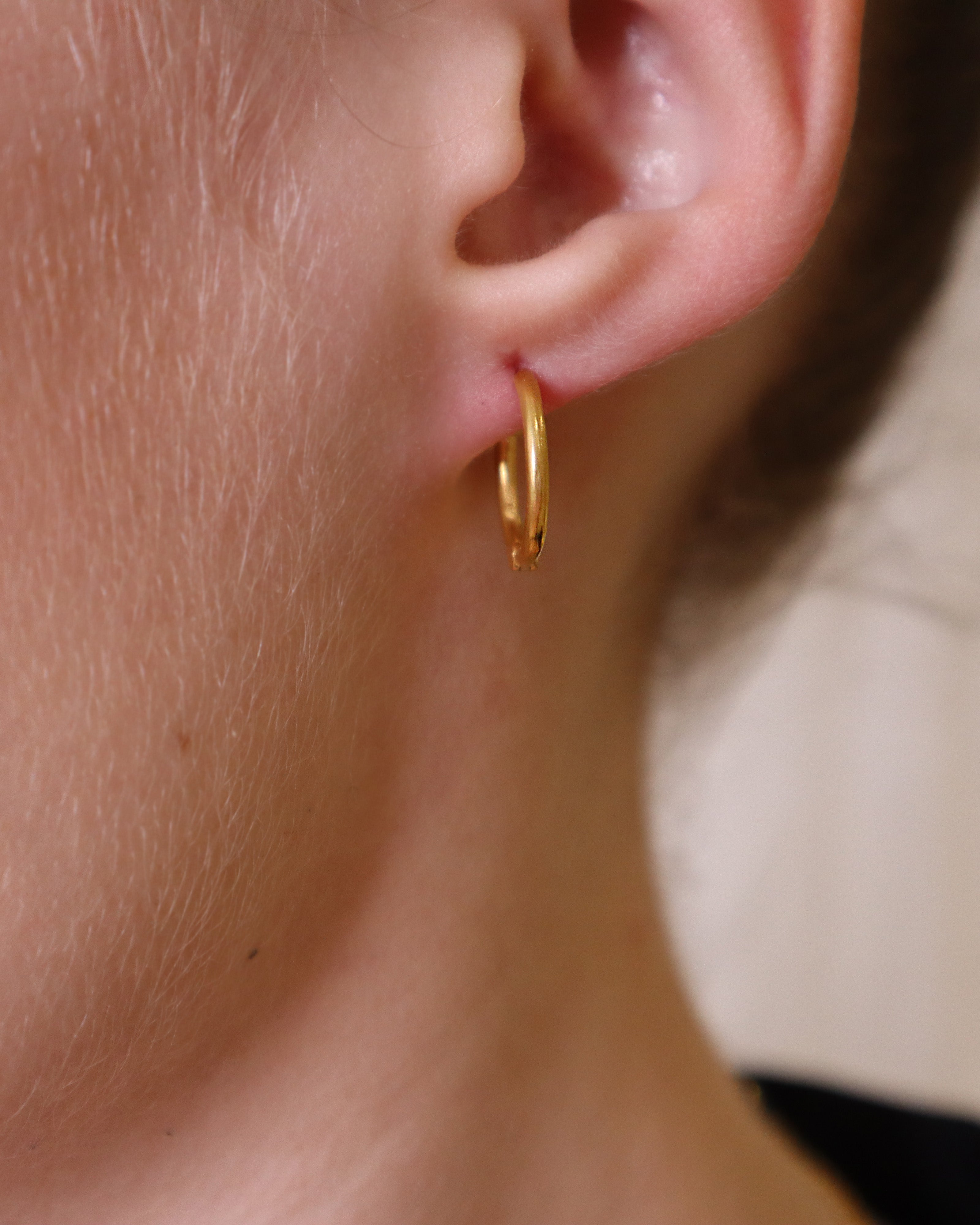 Model wearing gold mini hoop earrings with aqua chalcedony charms