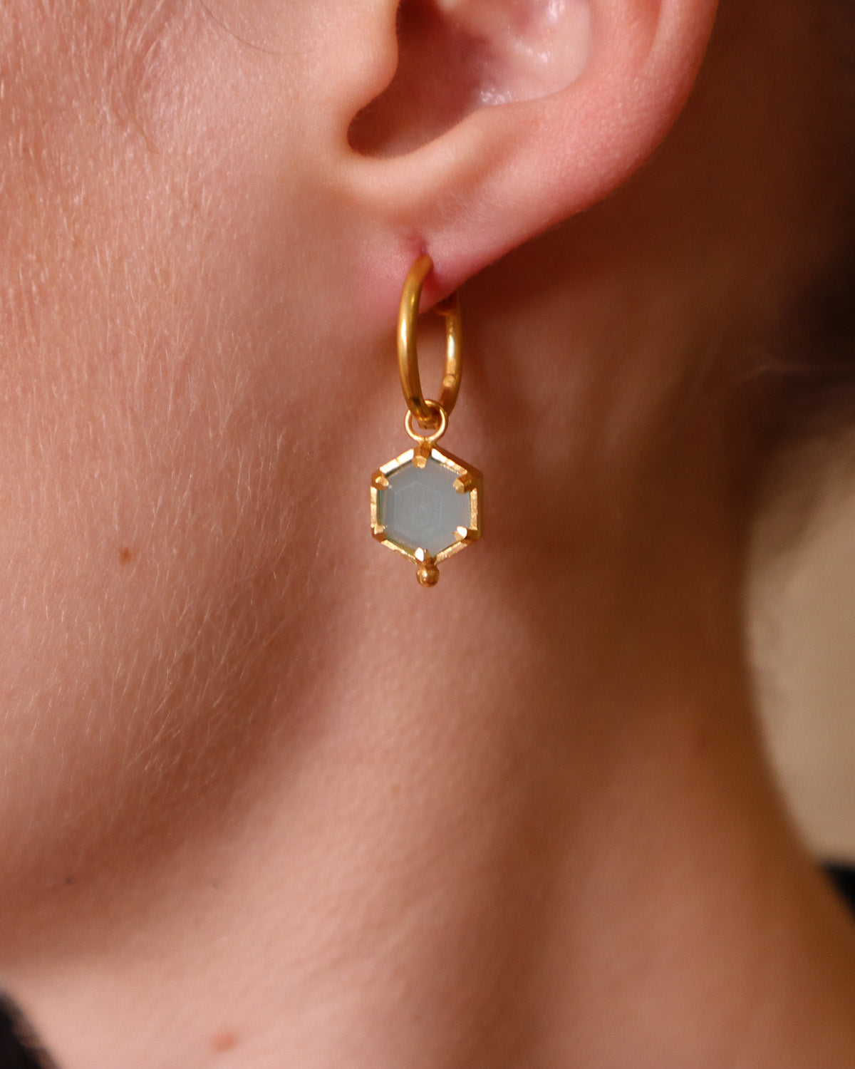 Side angle of gold mini hoop earrings with aqua chalcedony drop charms