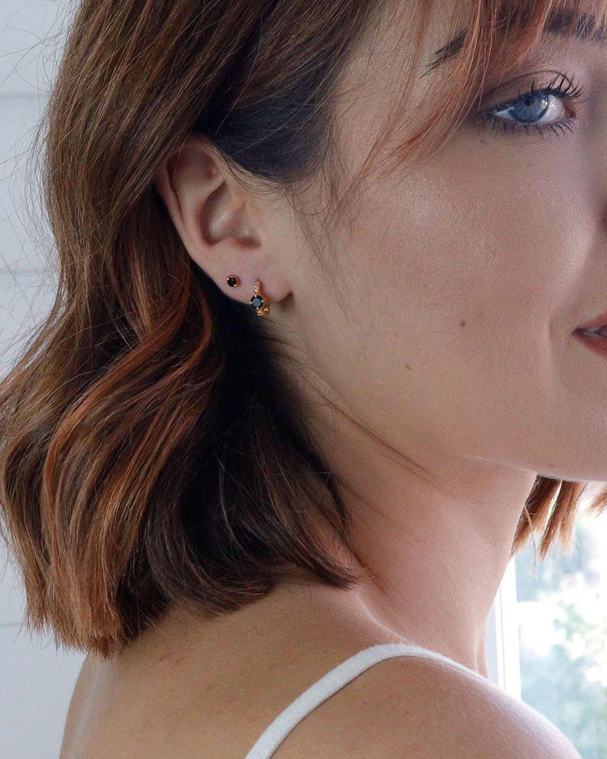 Close-up of gold mini hoops with black spinel gemstones and pearls
