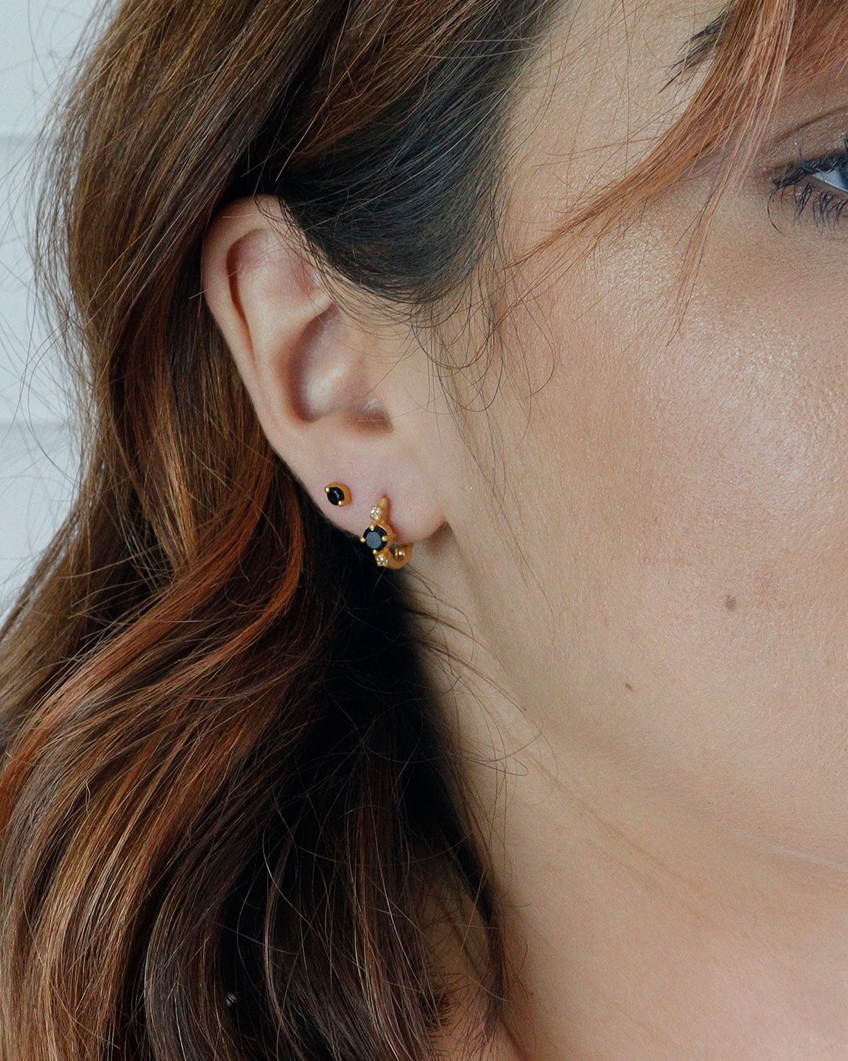 Detailed view of black spinel gemstones and pearl accents on mini hoops