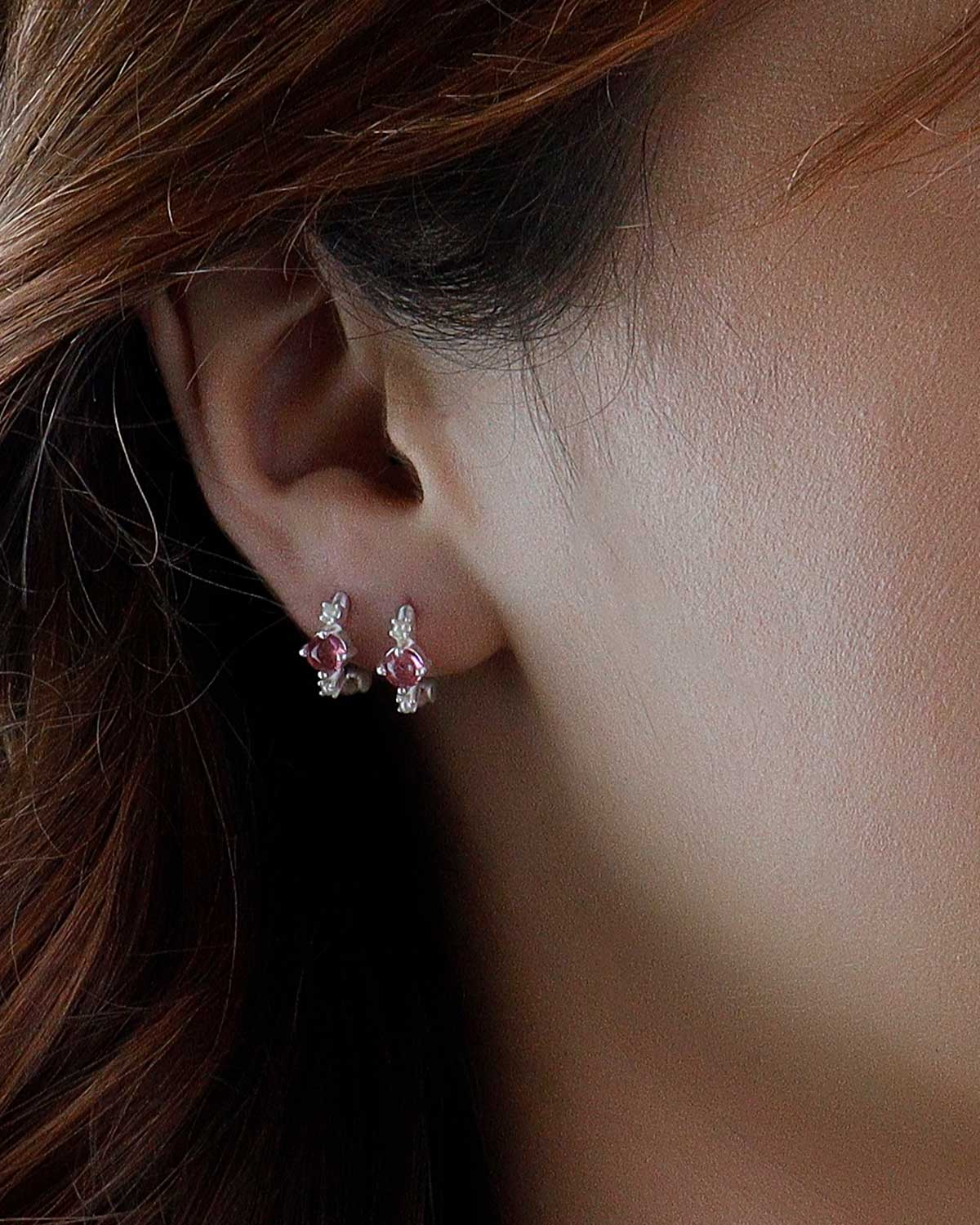 Close-up of silver mini hoops with tourmaline stones and pearl accents