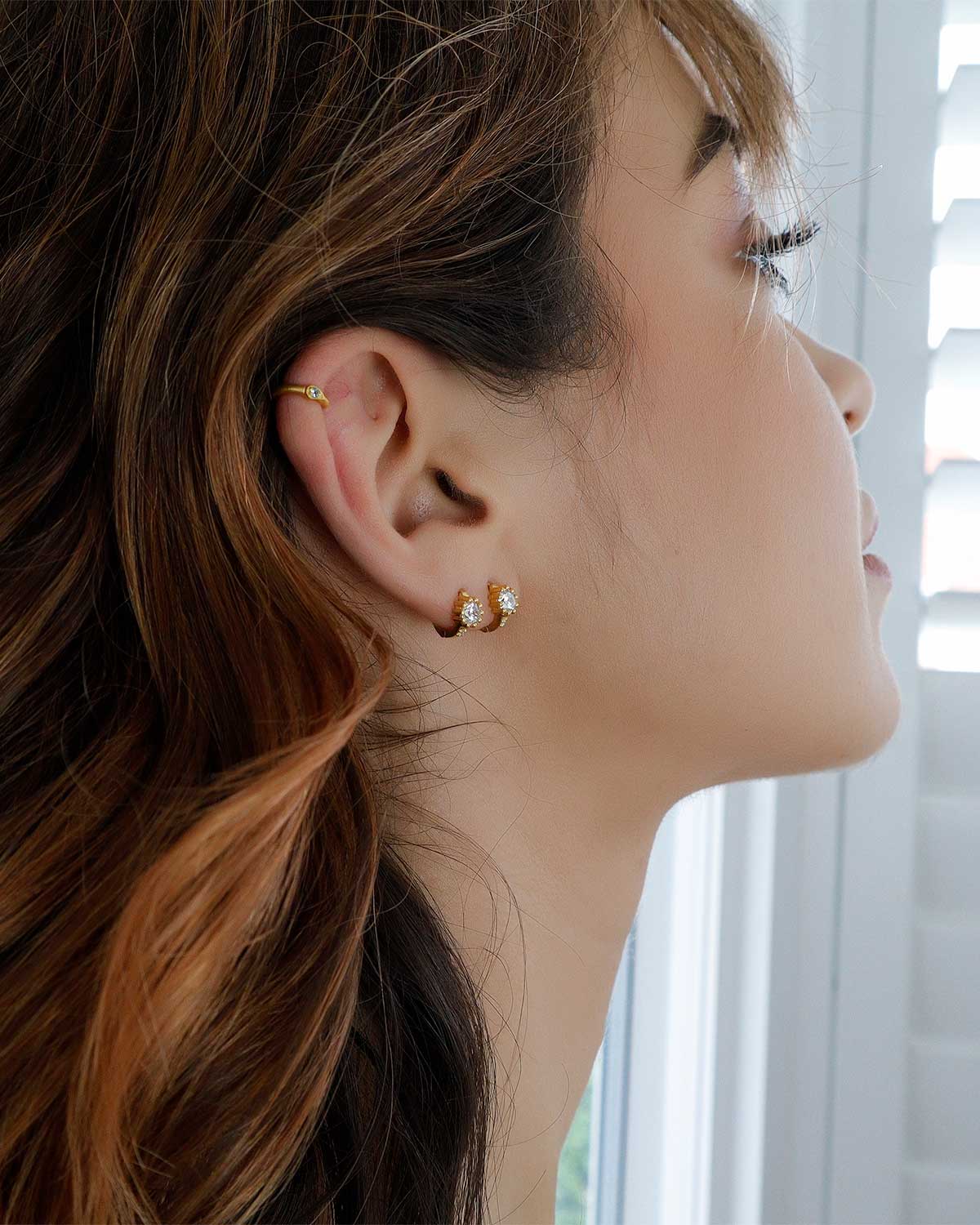 Side view of gold mini hoop earrings with pink amethyst and cubic zirconia