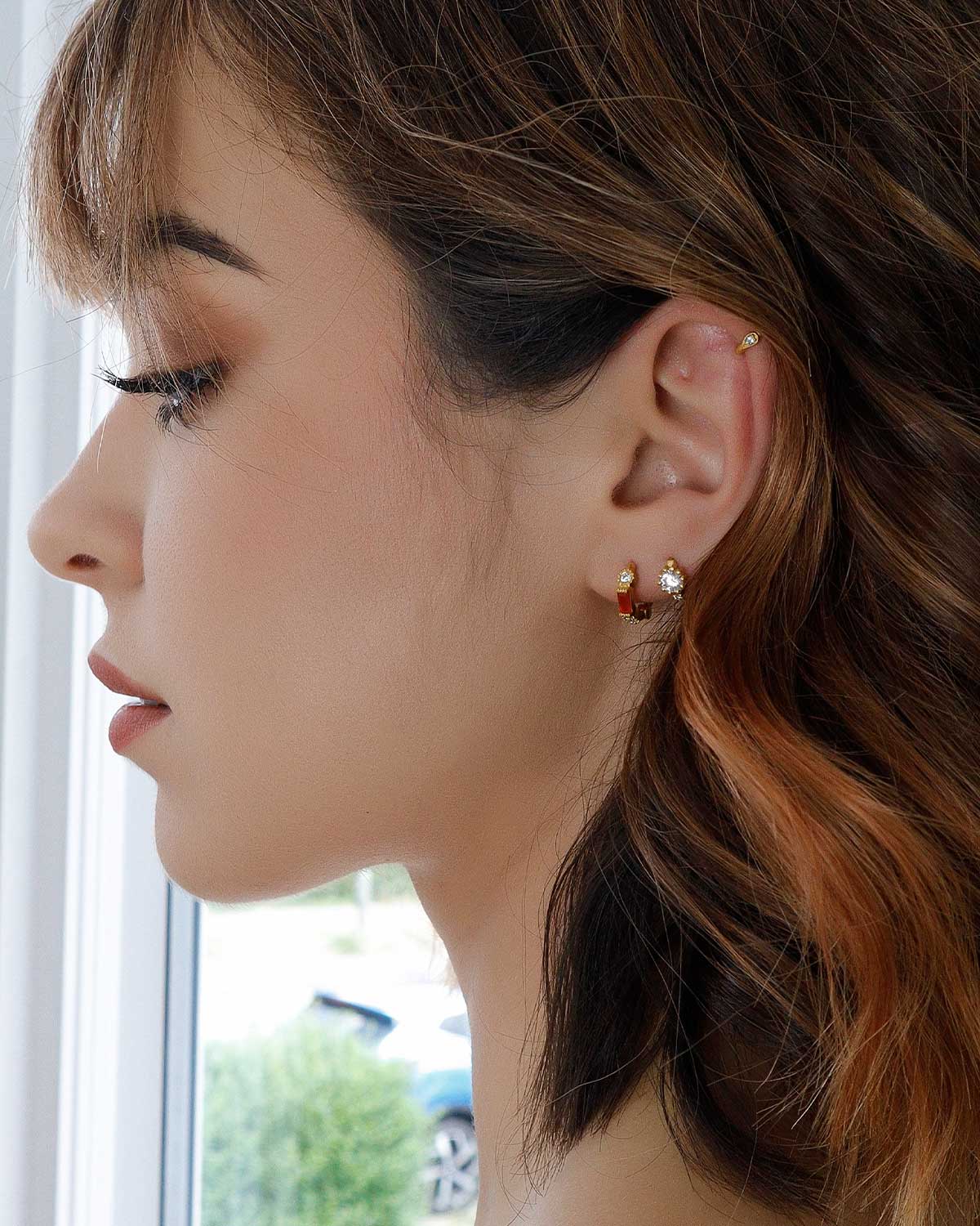 Detailed view of gold huggie earrings with mixed gemstones and matte finish