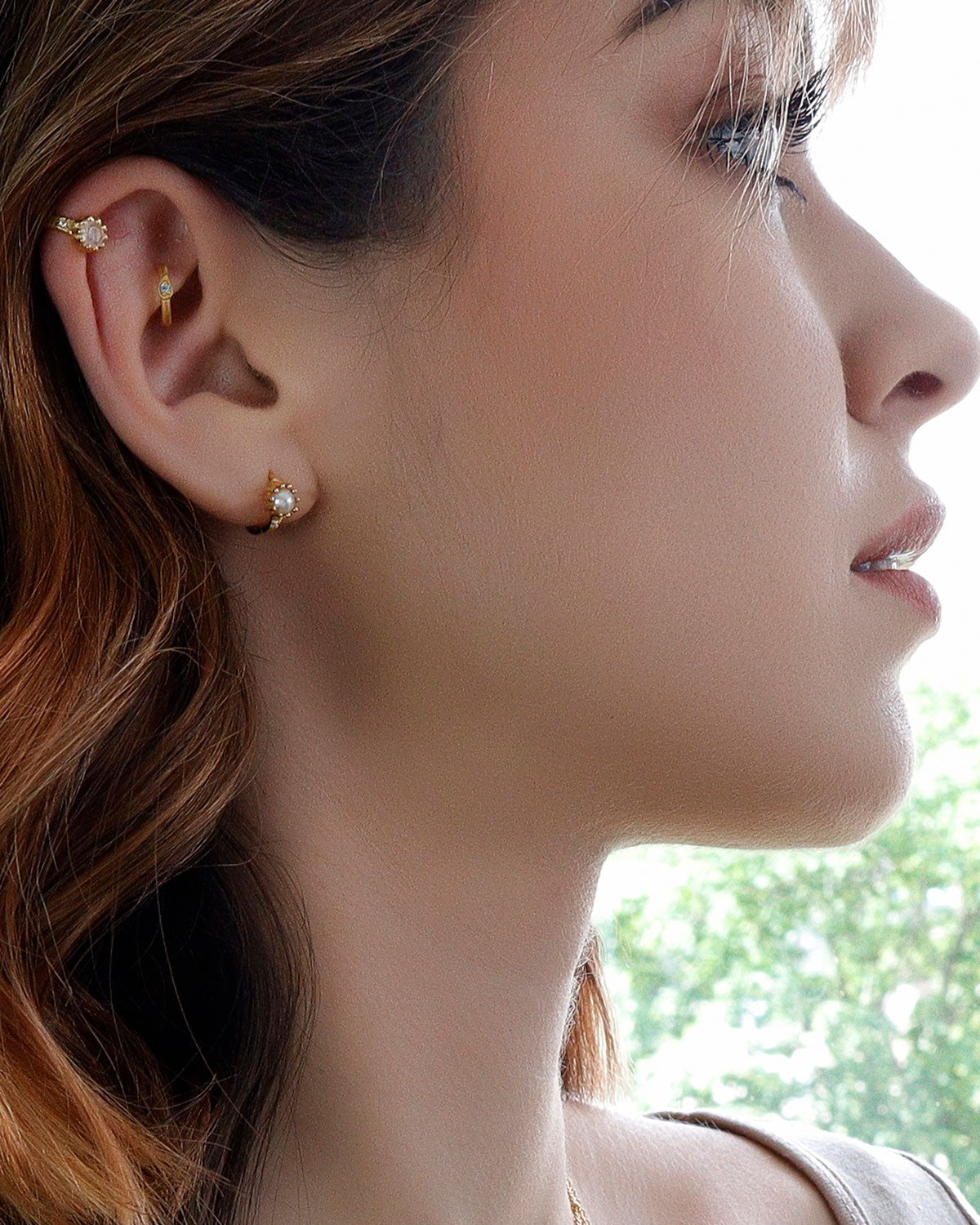 Close-up of gold huggie earrings with pink amethyst and cubic zirconia stones