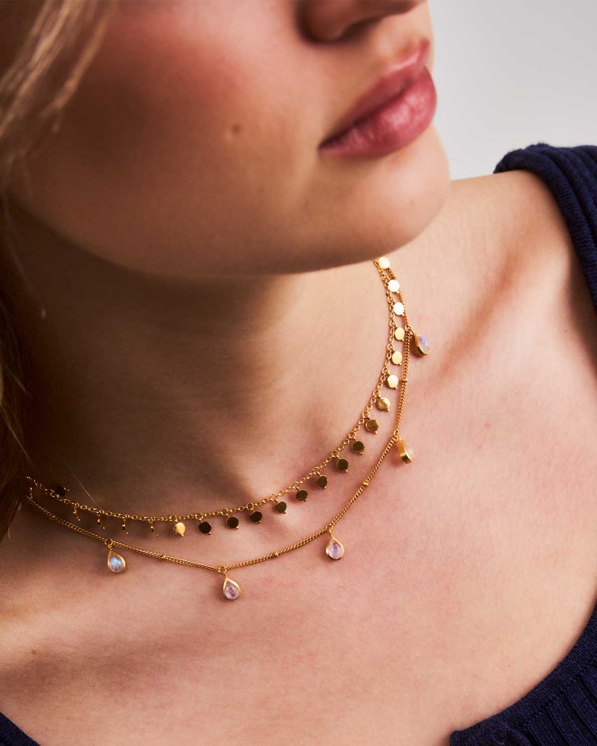 Close-up of a woman wearing a gold natural teardrop moonstone pendant