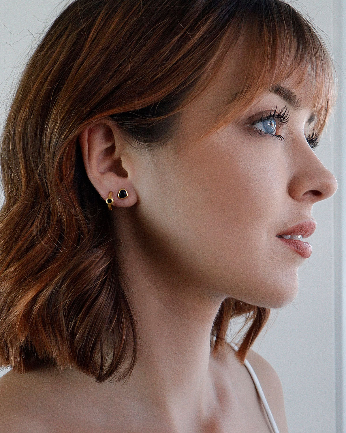 Model wearing gold mini hoop earrings with black spinel gemstones