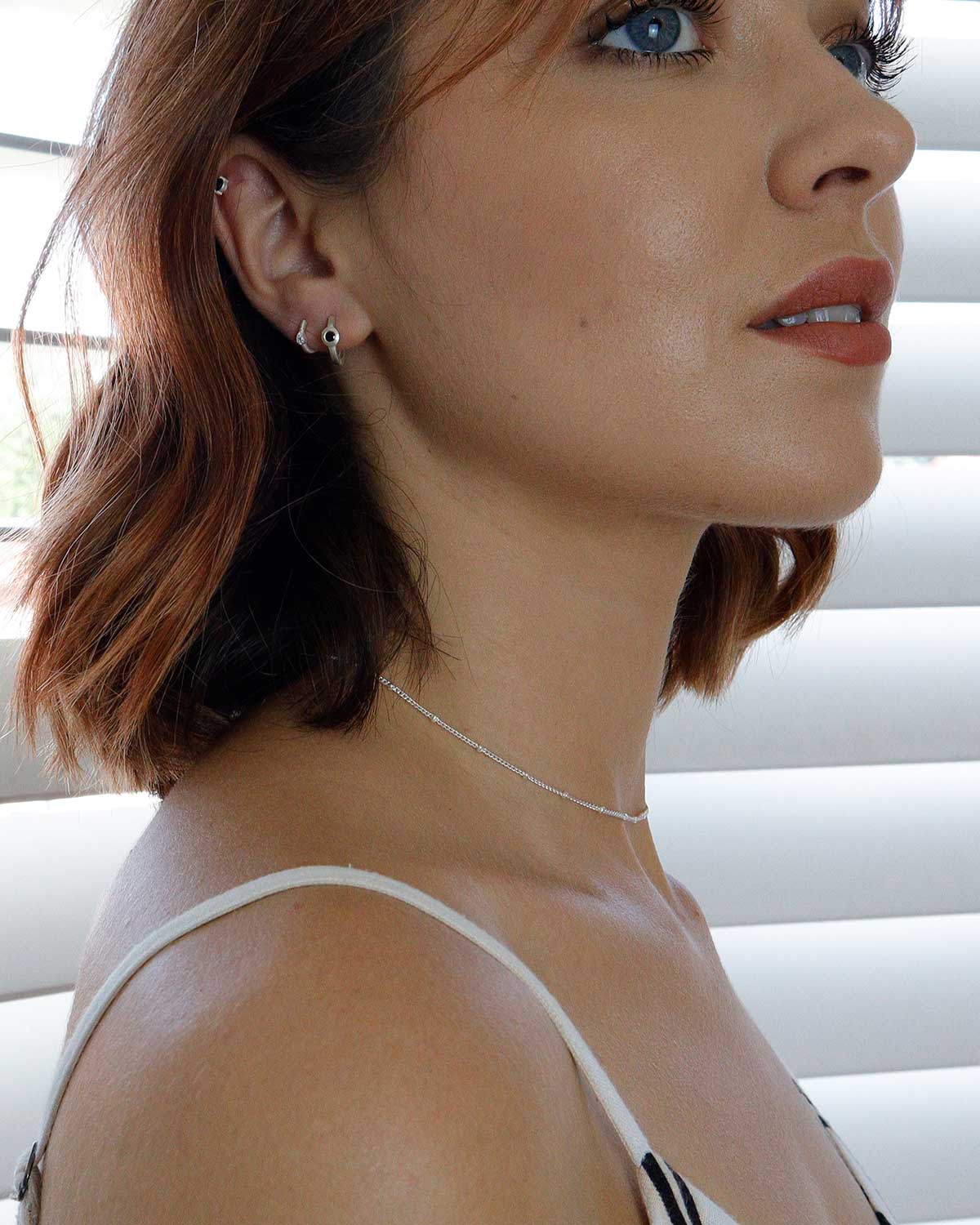 Model wearing silver mini hoop earrings with black spinel gemstones
