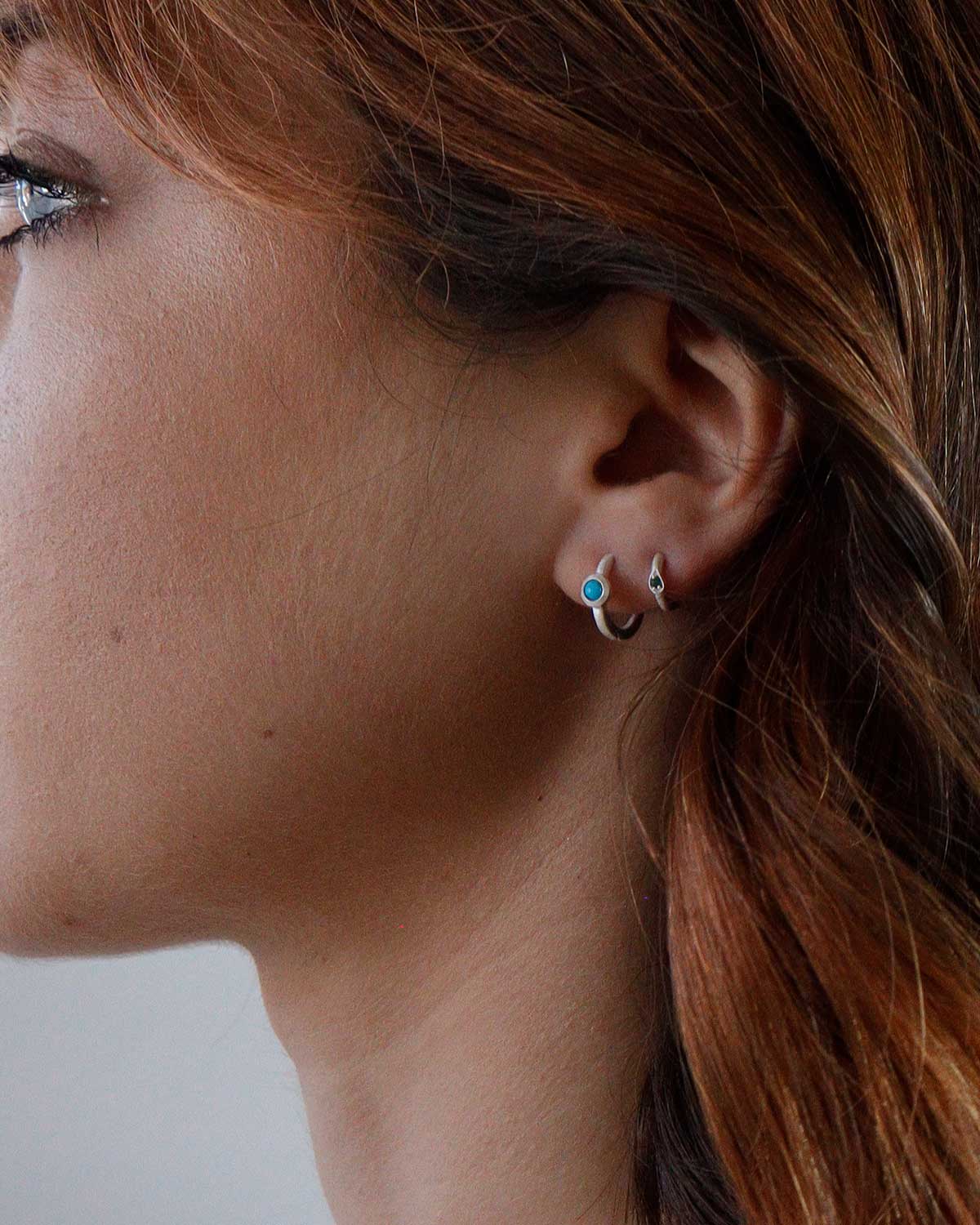 Model wearing simple silver mini hoop earrings with gemstones
