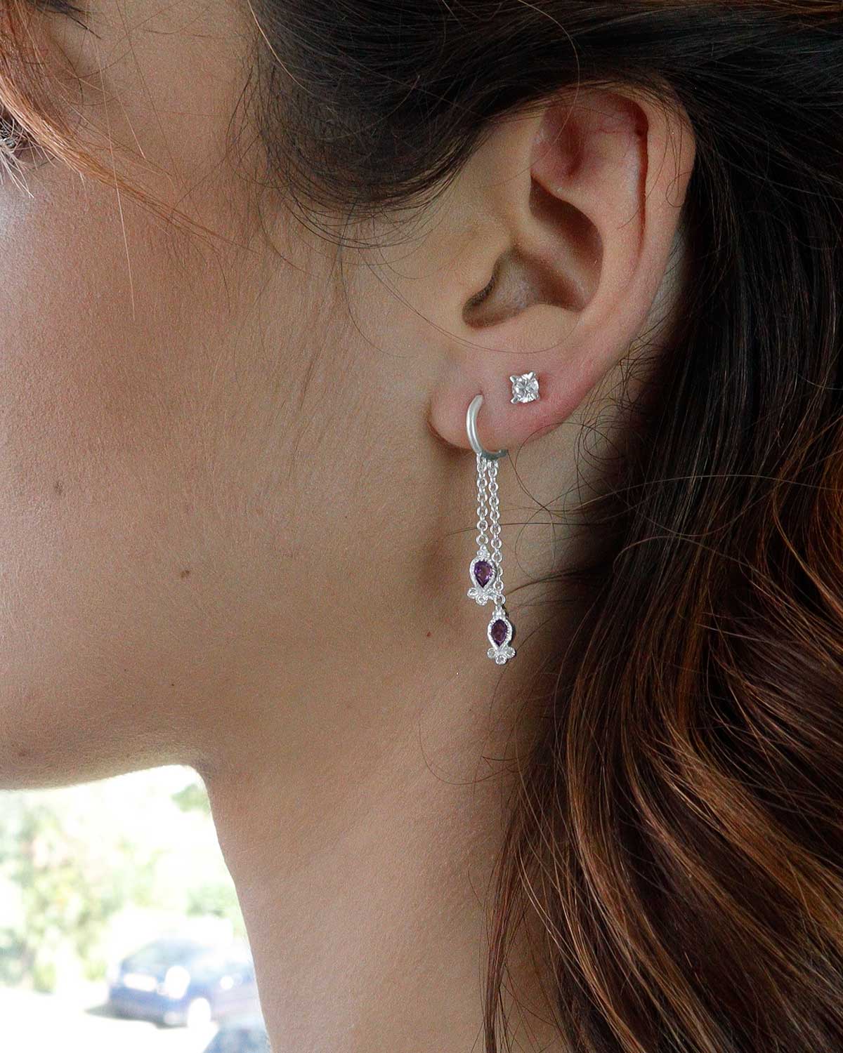 Close-up of mini hoop earrings with hand-cut amethyst gemstones and crystal detail