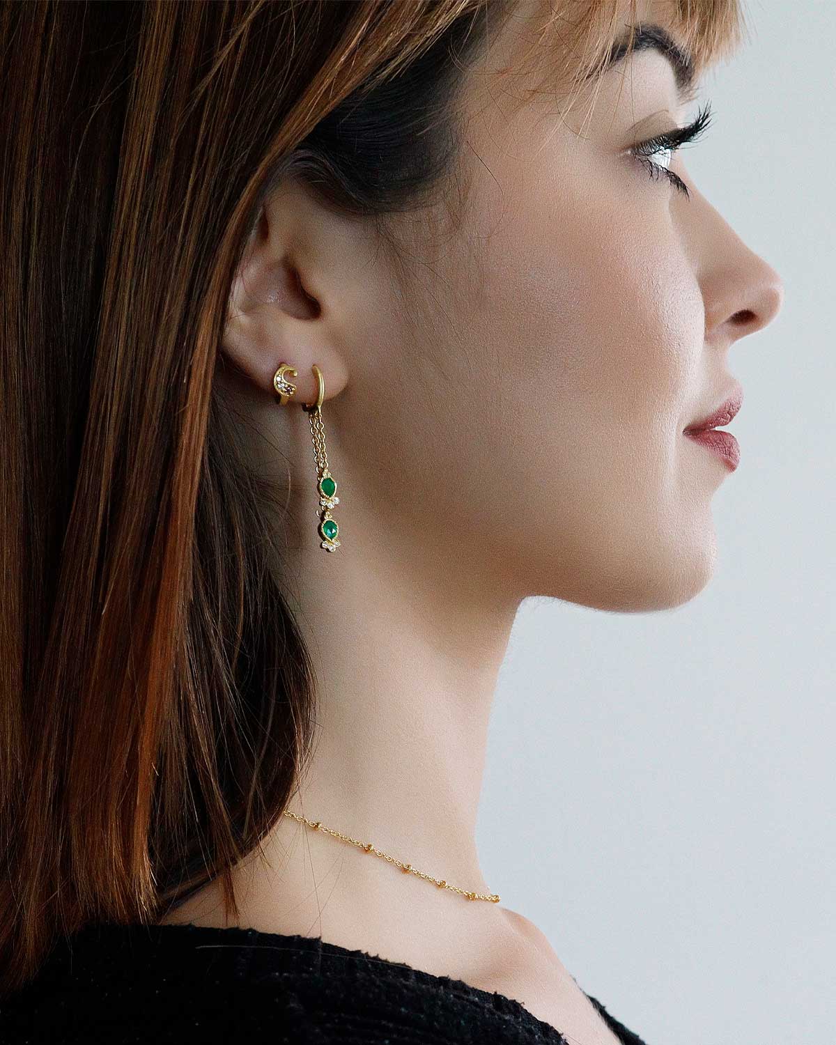 Model wearing mini hoop earrings with emerald green onyx gemstones