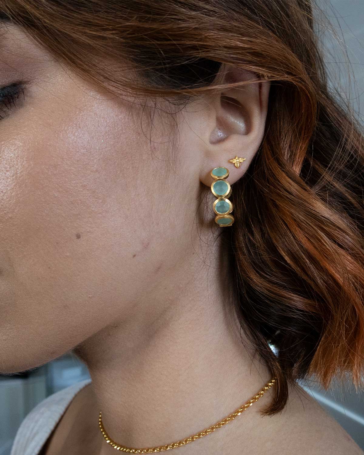 Close-up of gold hoop earrings with aqua calcedony gemstones