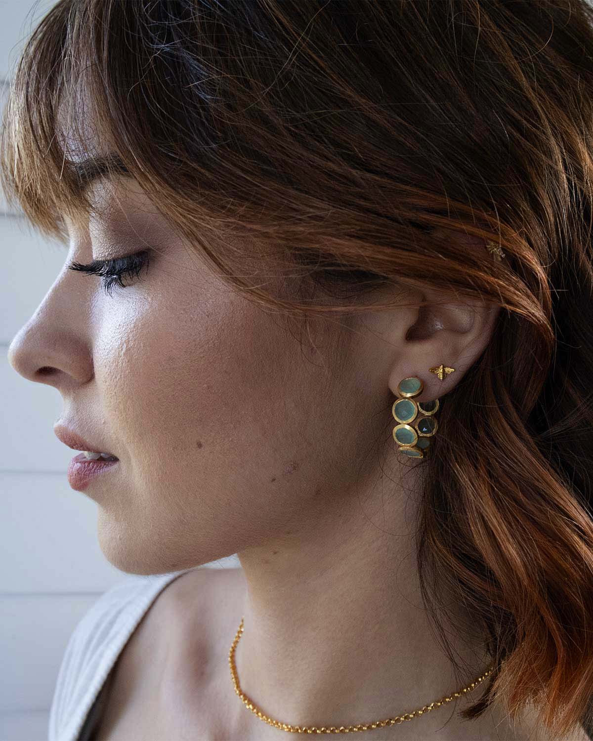 Model wearing gold hoop earrings with aqua calcedony gemstones