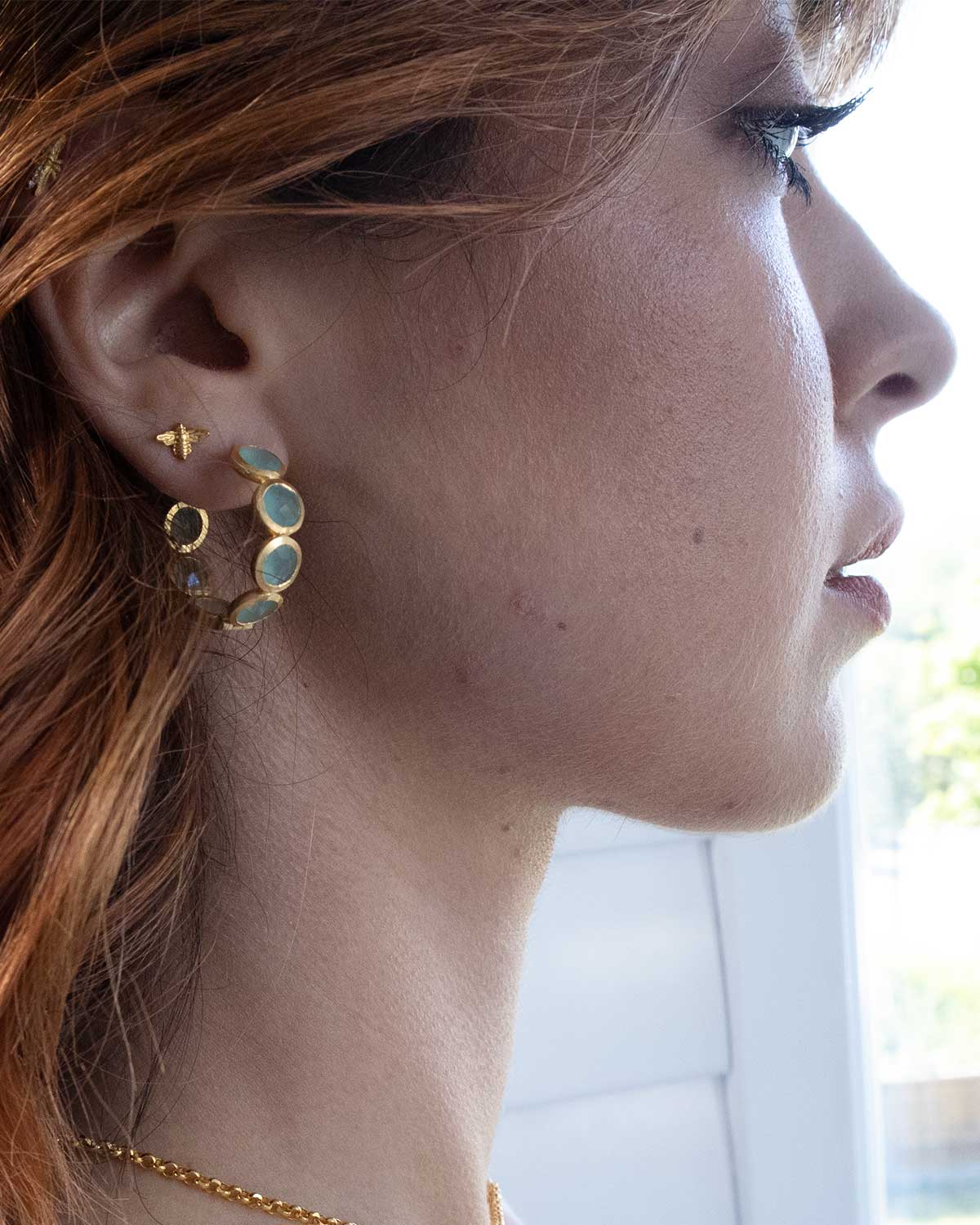 Side angle of gold hoop earrings with aqua calcedony gemstones