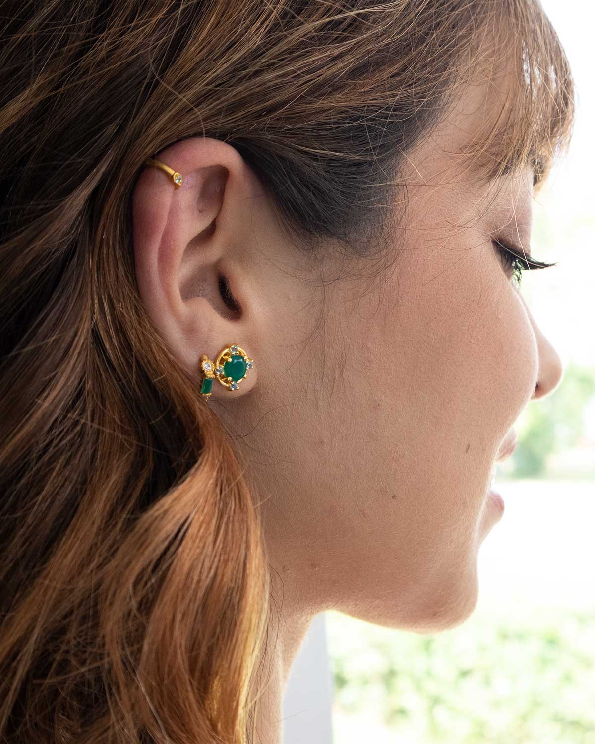 Close-up of gold stud earrings with green onyx and blue topaz stones