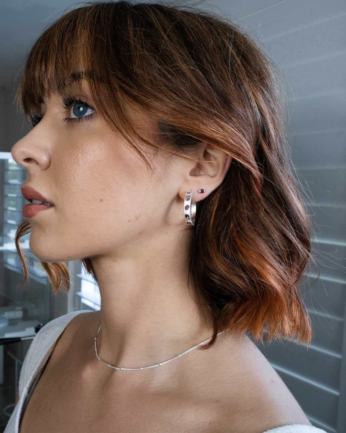 Model wearing silver hoop earrings with multi colour tourmaline gemstones
