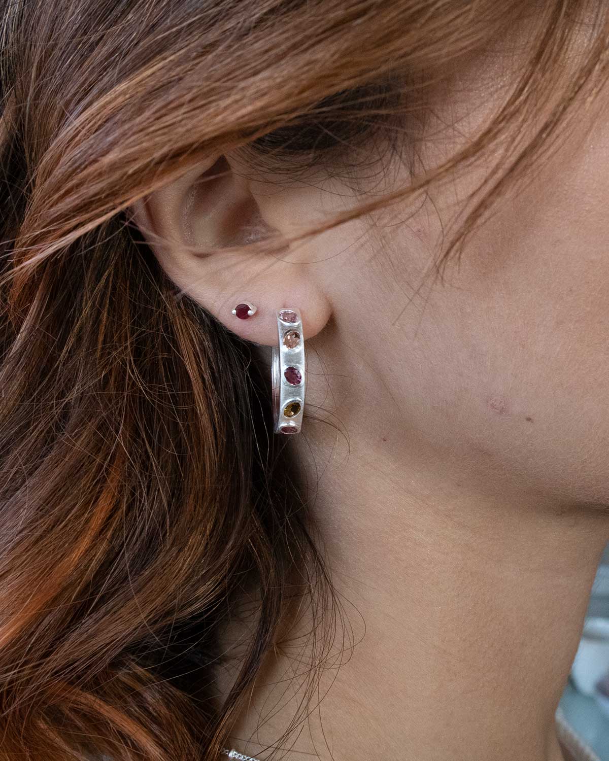 Side angle of silver hoops showing textured finish and tourmaline gemstones