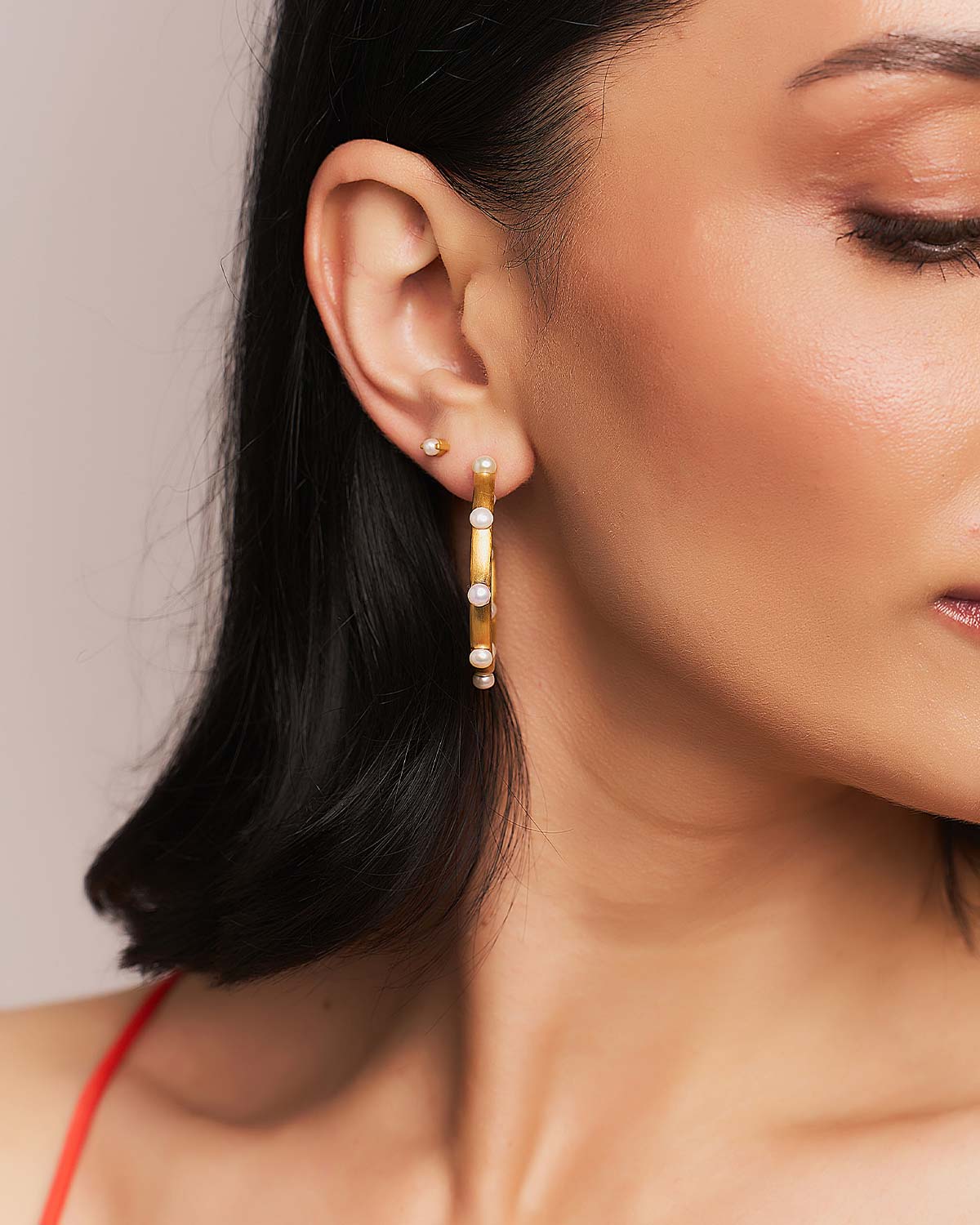 Detailed view of handcrafted gold hoops with multiple pearls, polished finish