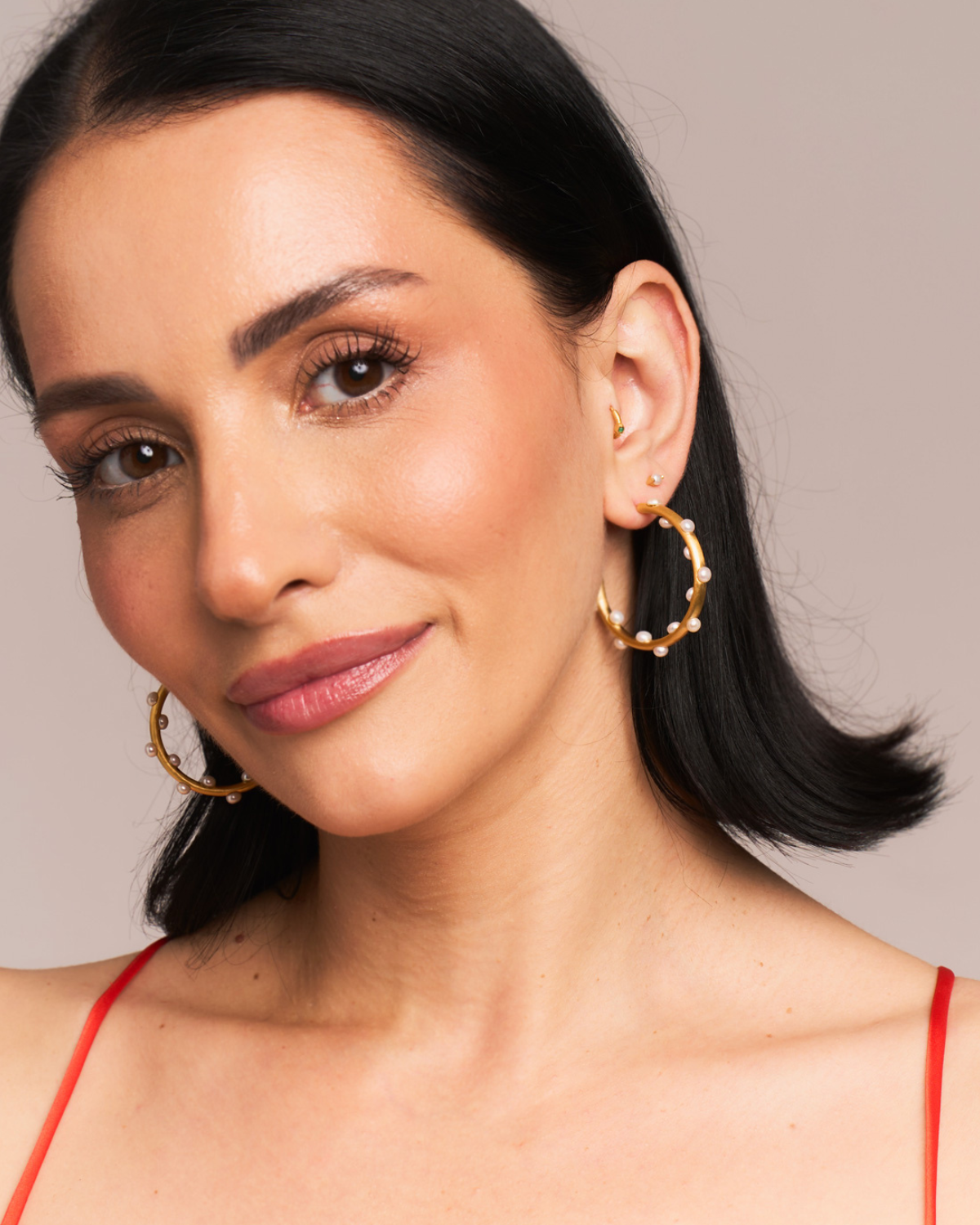 Model wearing statement gold hoops with natural pearl embellishments
