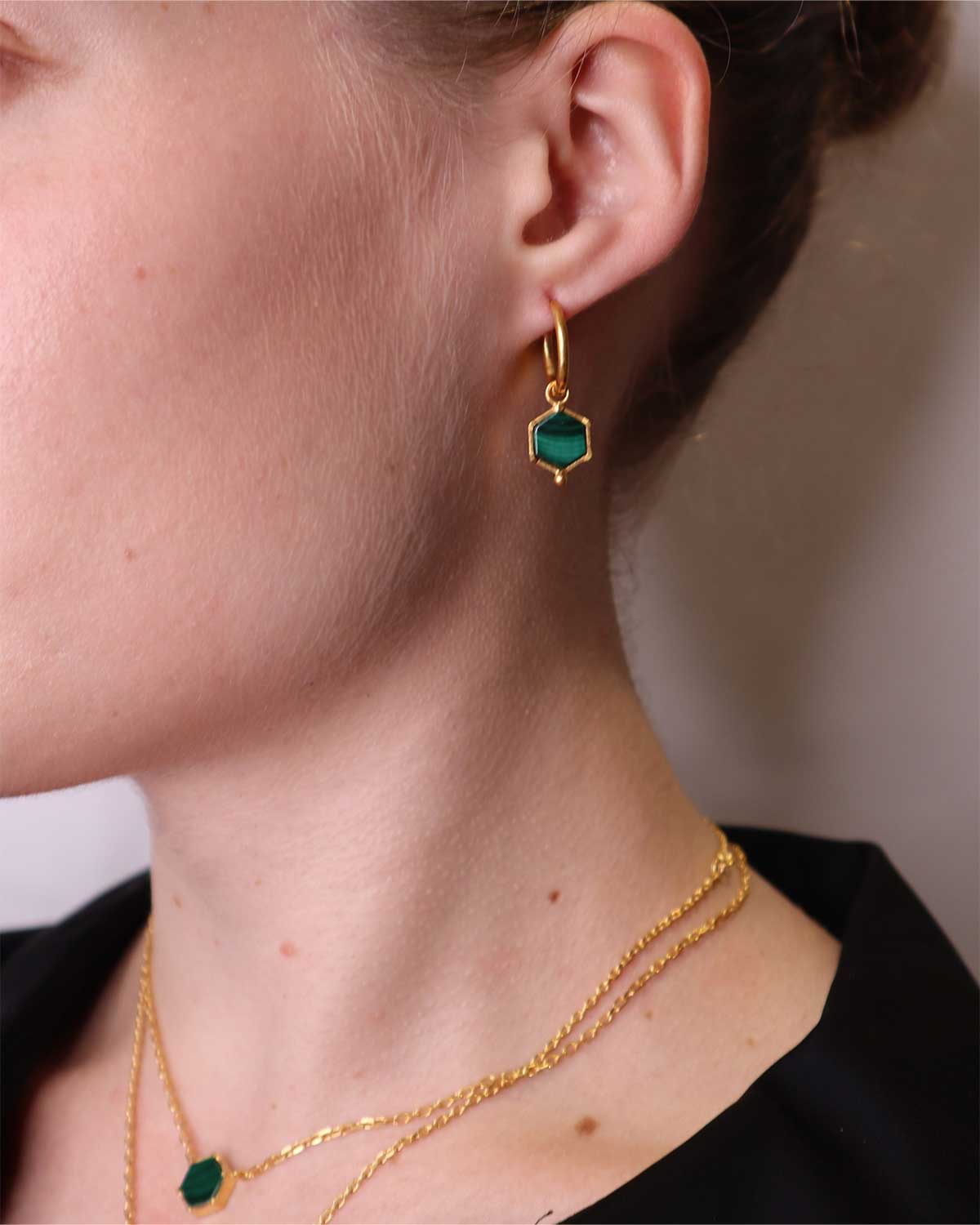Model wearing gold mini hoop earrings with natural malachite gemstones